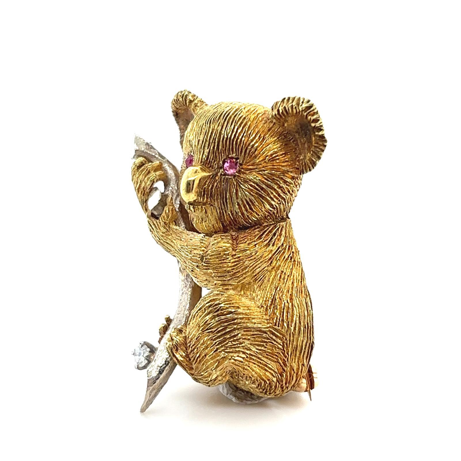A ruby and diamond koala brooch in yellow gold, circa 1960.

This charming vintage koala pin brooch is beautifully made. Its facial features and fur are highly detailed.
He holds onto a contrasting white gold bamboo branch set with a round brilliant