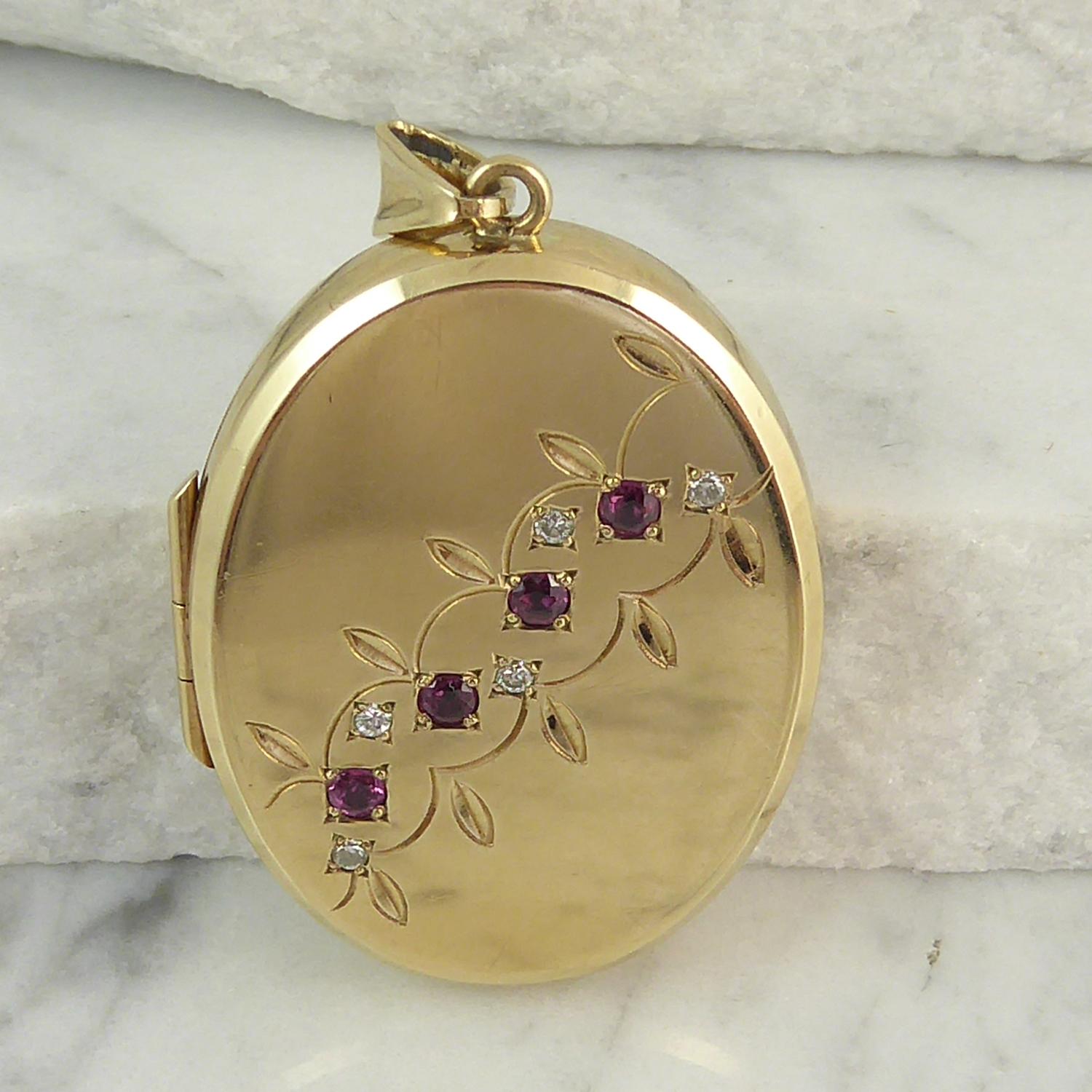 A vintage locket, oval shaped and with a bevelled edge, in plain polished 9ct yellow gold.  The front of the locket is set with a row of four rubies bead set in square mounts and arranged on a diagonal from top right to bottom left and with a