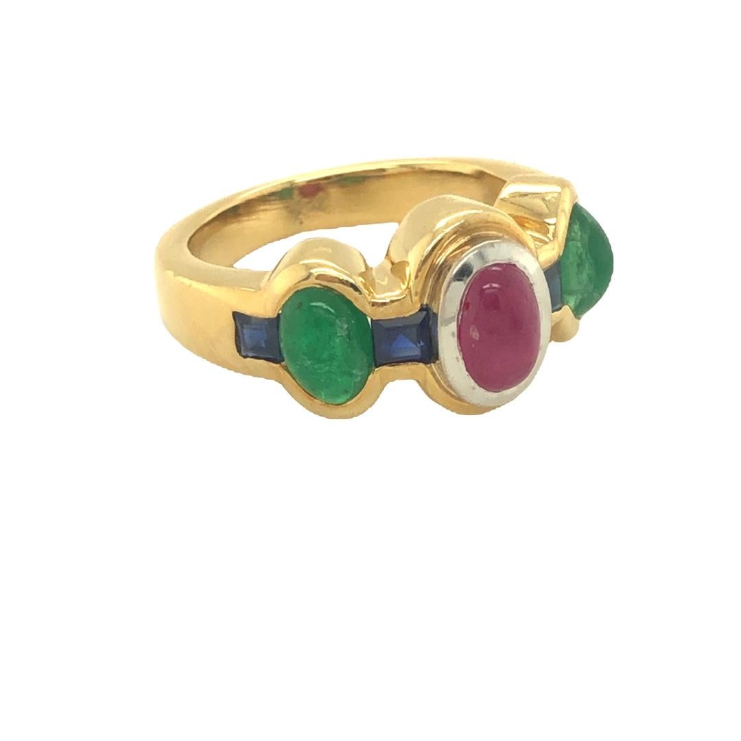 An exquisite ring adorned with multiple gemstones, including cabochon ruby, cabochon emerald, and square-cut sapphire. The central focus is the cabochon ruby, expertly showcased within a two-tiered bezel setting. This beautiful ring is expertly