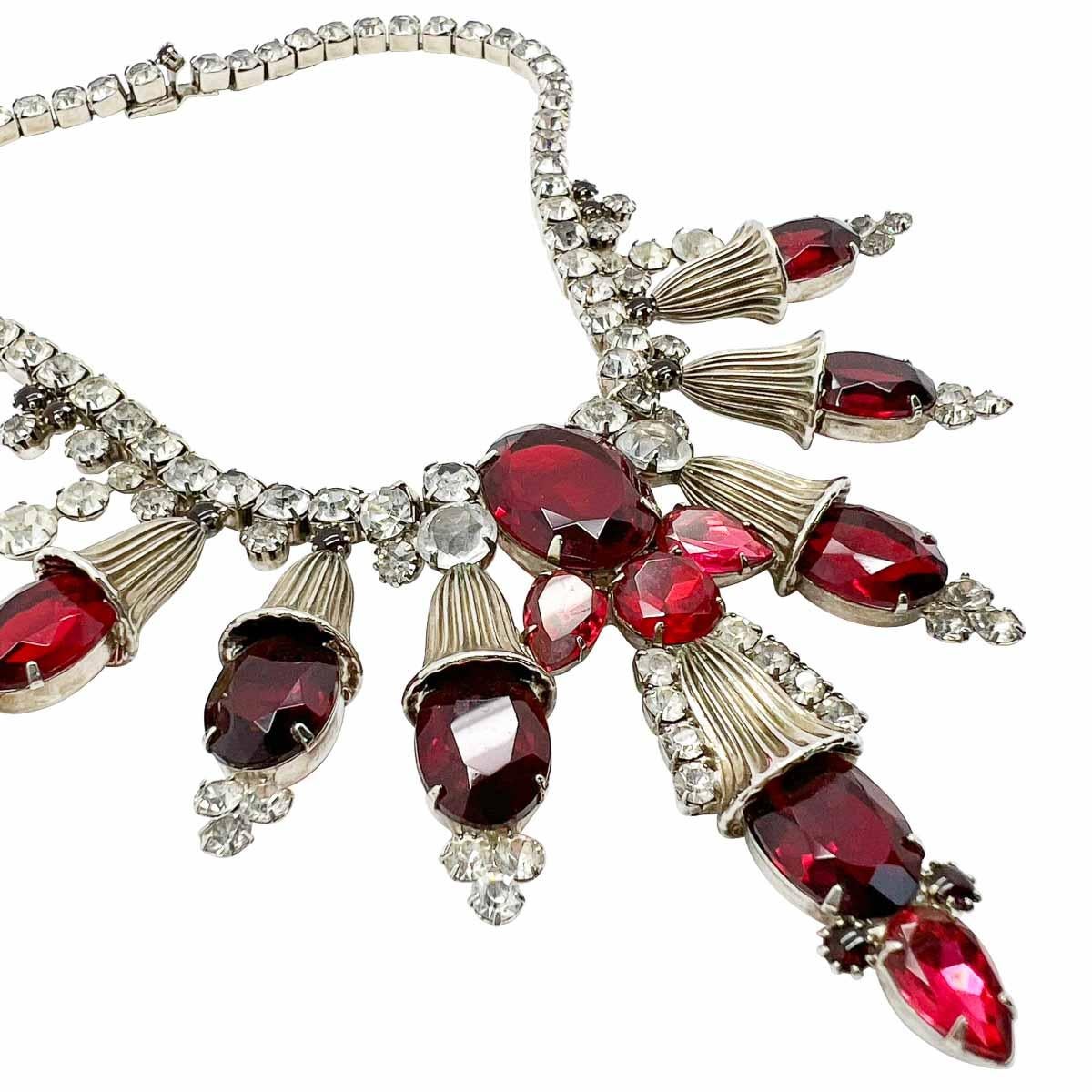 Ein prächtiges Vintage Ruby Statement Collar. Das raffinierte Design umfasst große rubinrote Glassteine inmitten großer Metallmotive und überlässt kein Detail dem Zufall. Bis hin zu den winzigen rubinroten Glascabochons in der Schließe und in der
