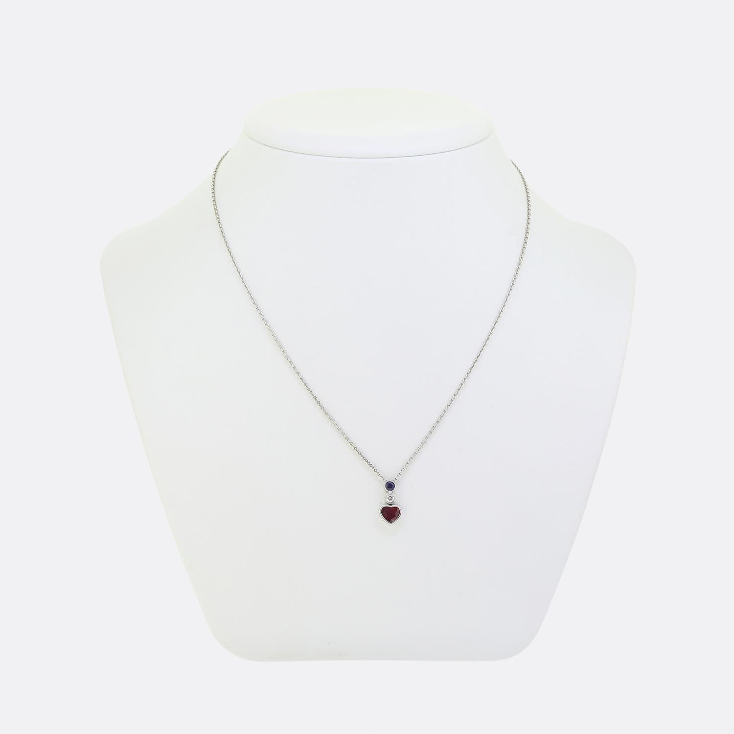 Here we have an 18ct white gold necklace featuring a romantic pendant design. The pendant showcases a heart-cut ruby with a rich red hue, complemented by a round faceted blue sapphire above. Completing the ensemble is a single round brilliant cut