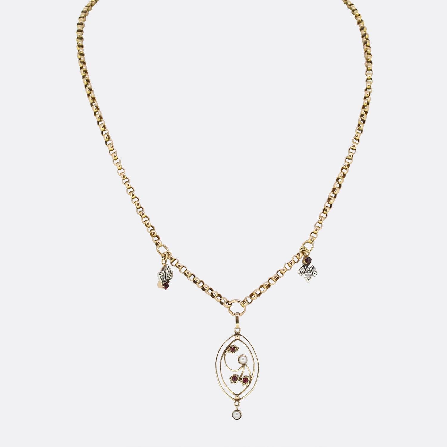 This is a vintage 9ct yellow gold belcher chain charm necklace. The necklace showcases an open oval shaped pendant featuring two natural pearls and three round red rubies. This pendant hangs freely from a belcher chain consisting of a duo of smaller