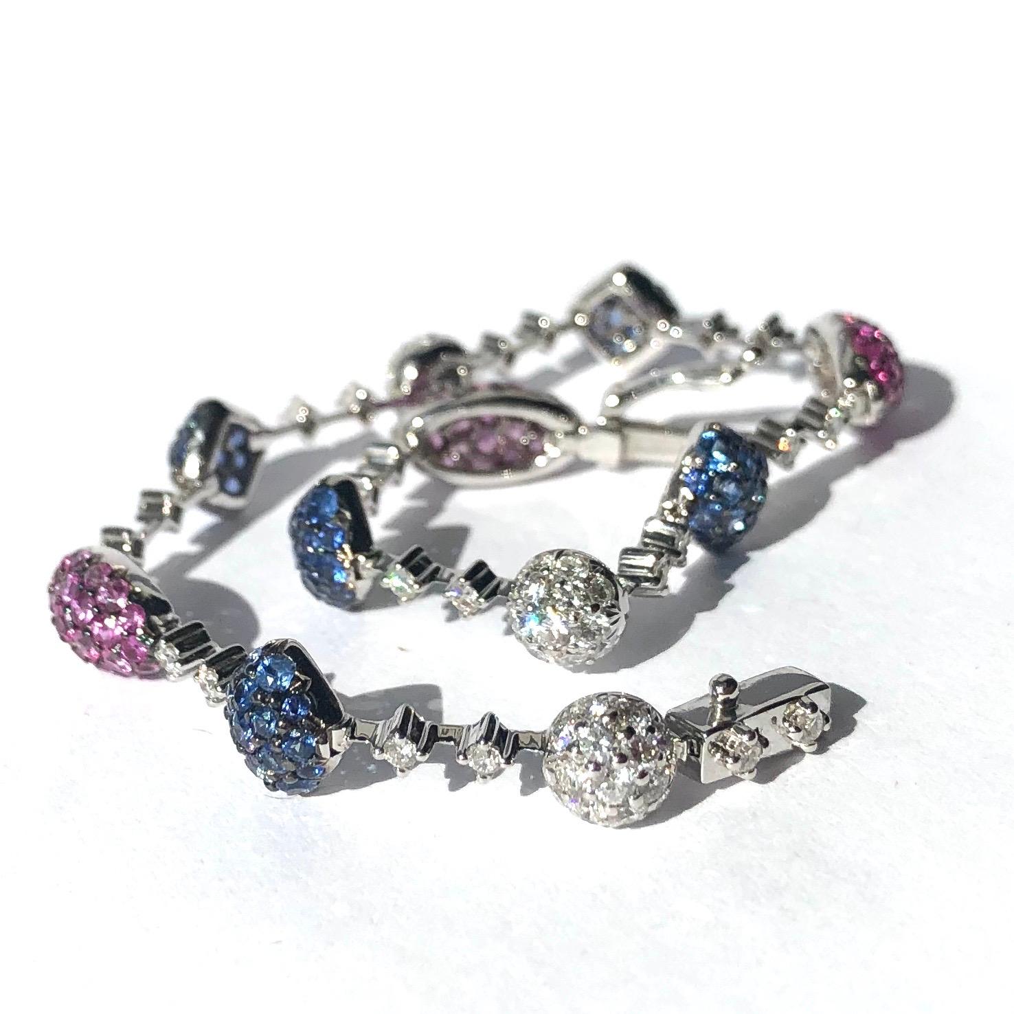 Dieses aufsehenerregende Armband ist mit glitzernden, tiefrosa Rubinen, blauen Saphiren und leuchtenden Diamanten geschmückt. Die Rubine sind in geschwungene ovale Felder gefasst, die durch ein Glied verbunden sind, das auch zwei Diamanten sowie die