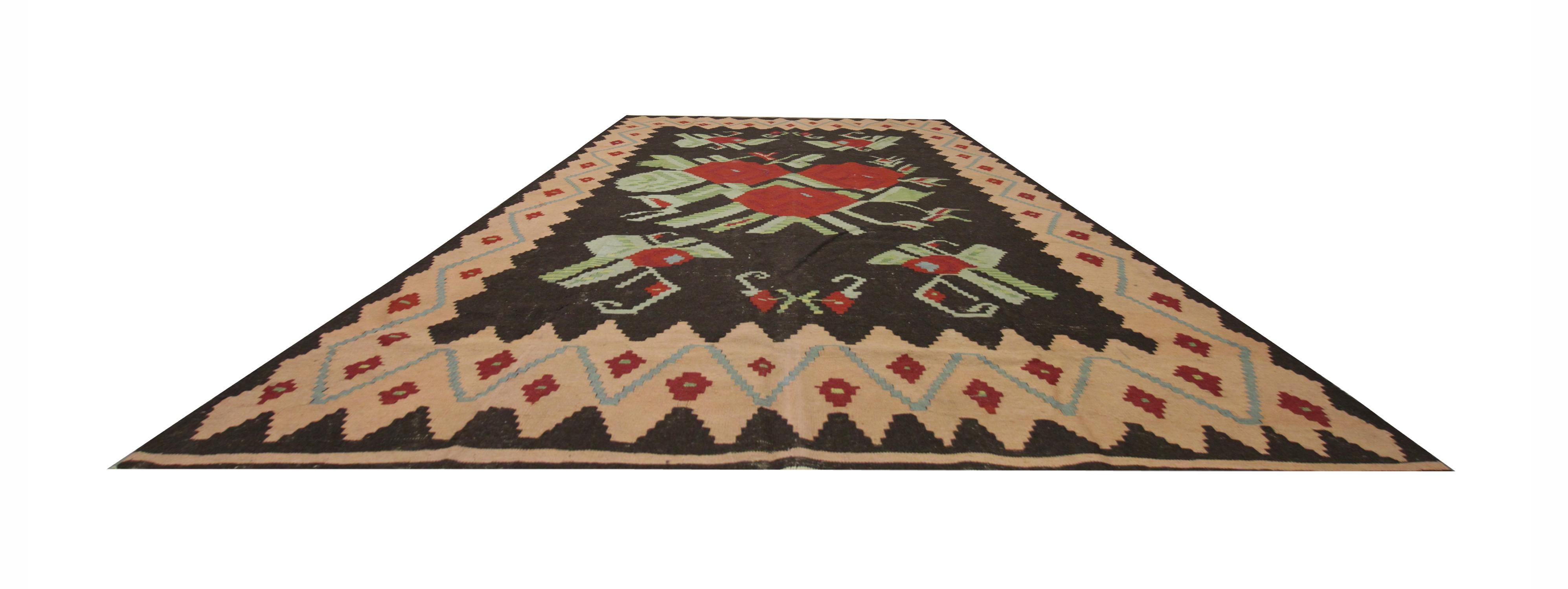Handwoven red roses and their foliage sit beautifully against a deep brown background to create the centrepiece for this rug. The main border is a pink zig-zag with blue and red details throughout. Detailed with a simple cream fringe on two sides,