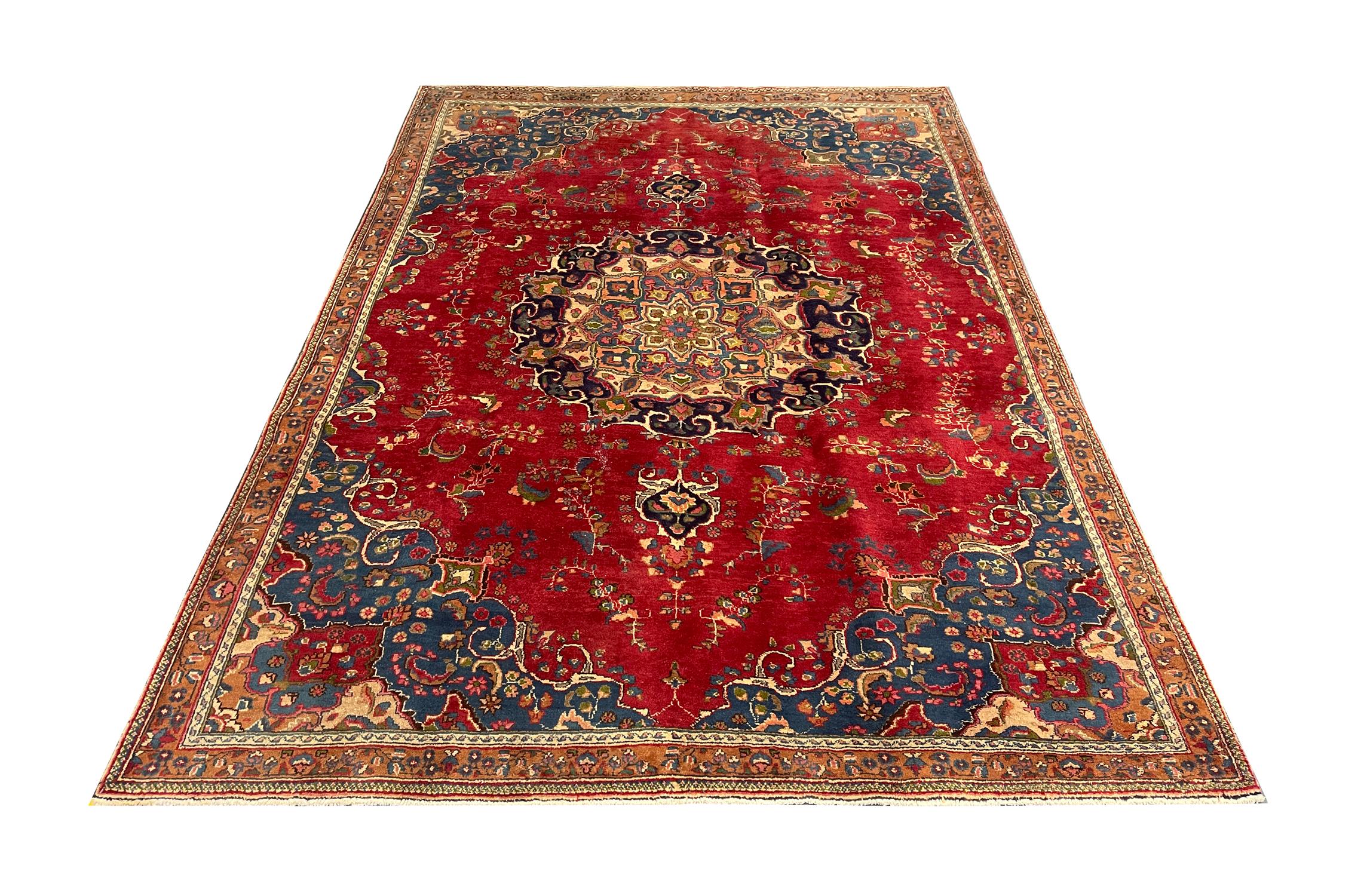 This unique wool area rug is a fantastic example of Turkish carpets woven in the late 20th century, circa 1970. The design features a large medallion and highly-decorative surrounding design. The rich red and blue colours used have been chosen to