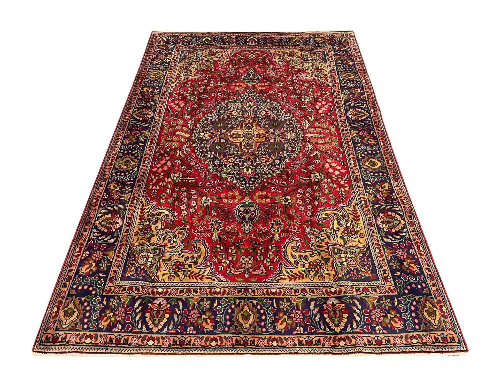 features a large medallion and highly-decorative surrounding design. Woven with a bold red background with blue, brown and beige accents that make up the intricate medallion and symmetrical surrounding design. The design and palette of this wool rug