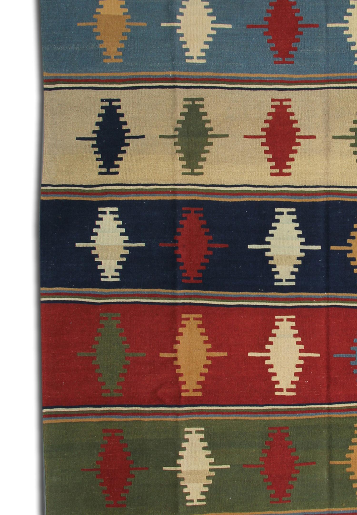 This beautiful antique rug features a simple rustic design handwoven with primary colours of red, blue and yellow. The design is linear and minimal with motifs running through in contrasting colours. Perfect for both traditional homes and