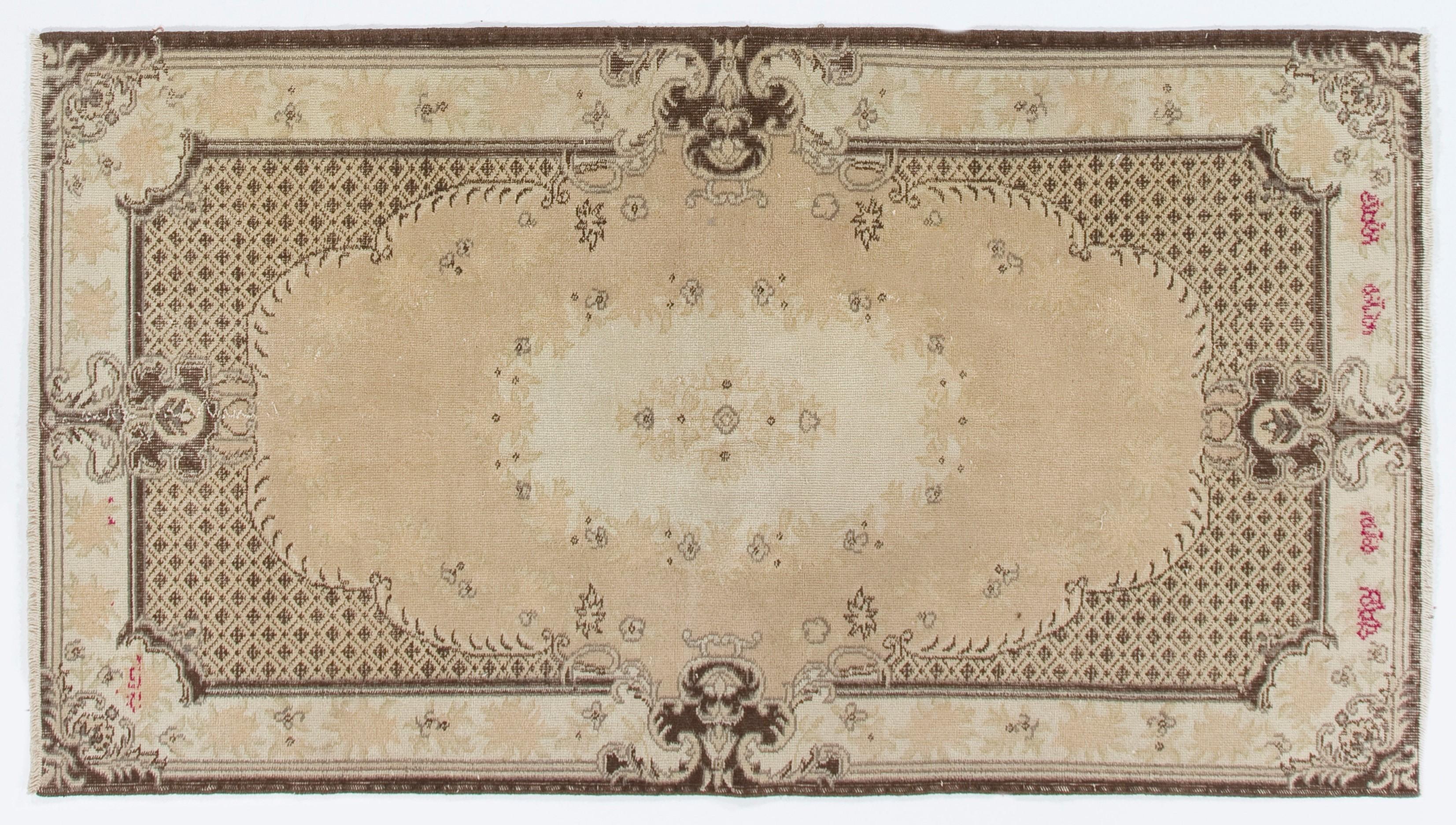 A vintage hand knotted Turkish rug with a central medallion design depicting rosettes and angular leaves in steel with touches of pink against a sandy cream field. 

The brown outlines of rosettes as well as the meandering brown lines running