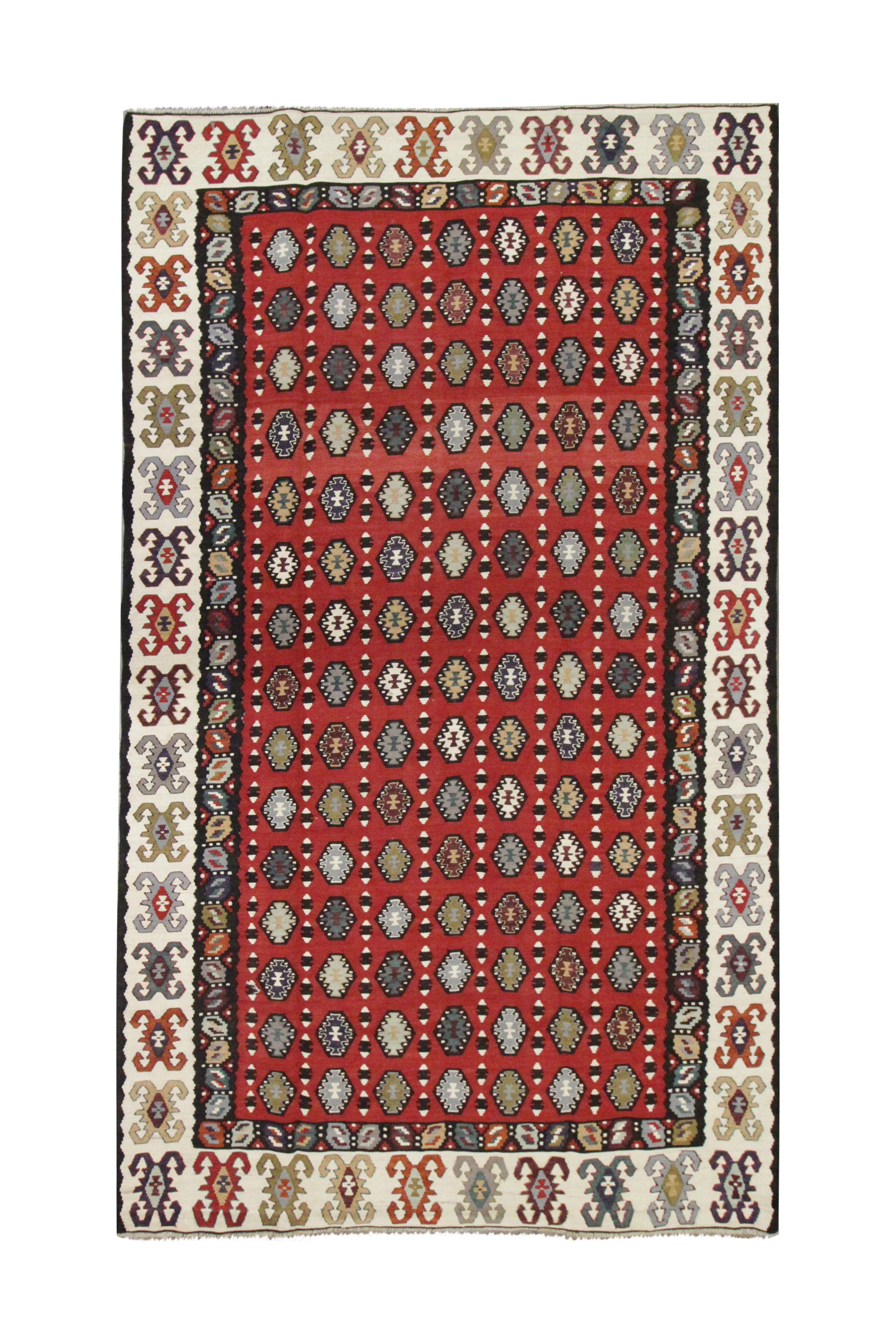 This vintage 1960s Serbian Pirot Kilim rug is a classic Bessarabian flatweave, known for its refined tribal motifs and bold colour palette. Handwoven from wool, it features a deep red and burgundy field accented with dark blue, ivory, grey, and