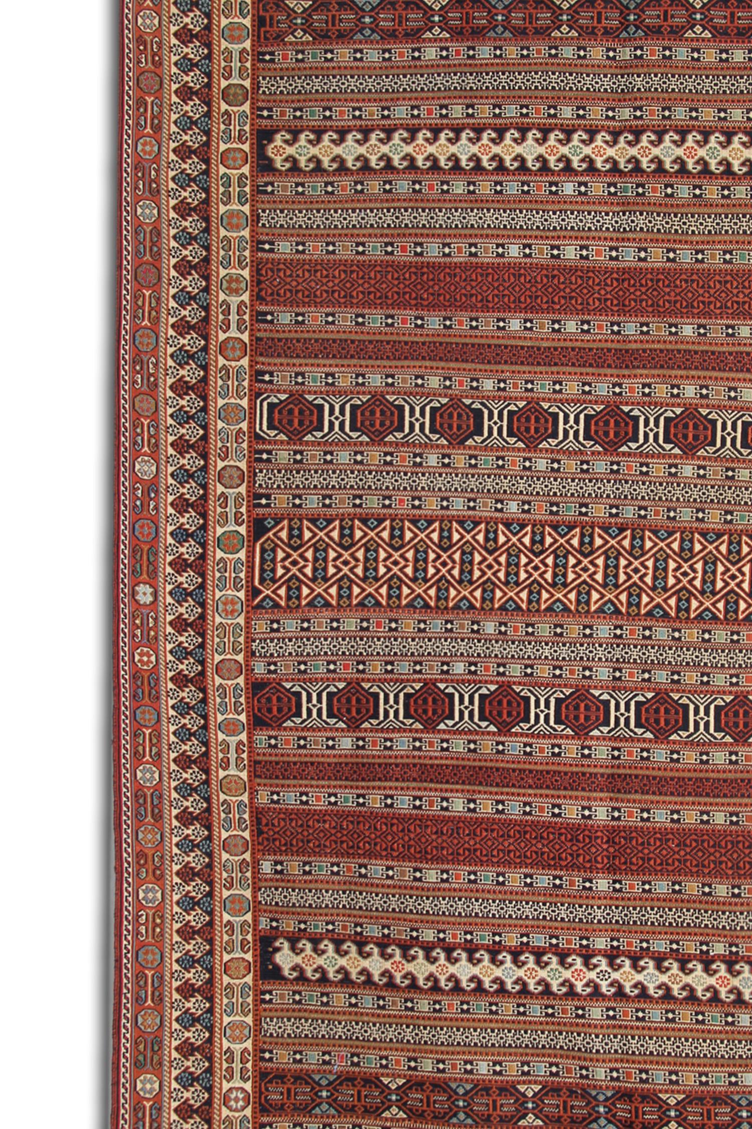 Dieser alte Soumak-Teppich wurde von Nomaden im späten 20. Jahrhundert, um 1980, hergestellt. Das Design zeigt ein rustikales, dekoratives Streifendesign, gewebt in einem tiefen Rot mit Akzentfarben in Rostbeige und Creme. 
Mit geometrischen