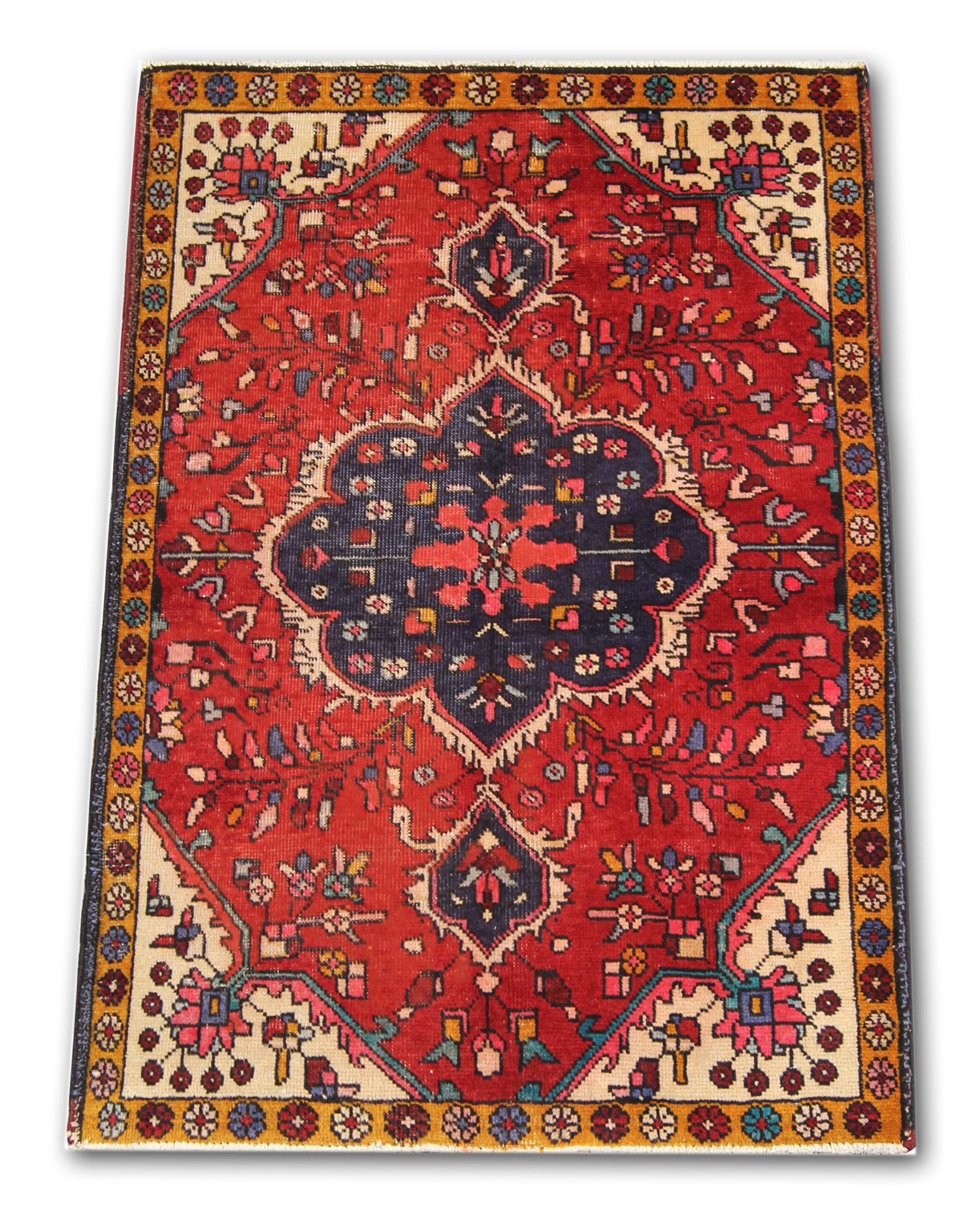 This elegant piece was woven by hand and featured a rich red background with a large central medallion woven in deep blue, with a decorative surrounding design and a simple border. With orange, blue and brown accents. Easily style this piece with