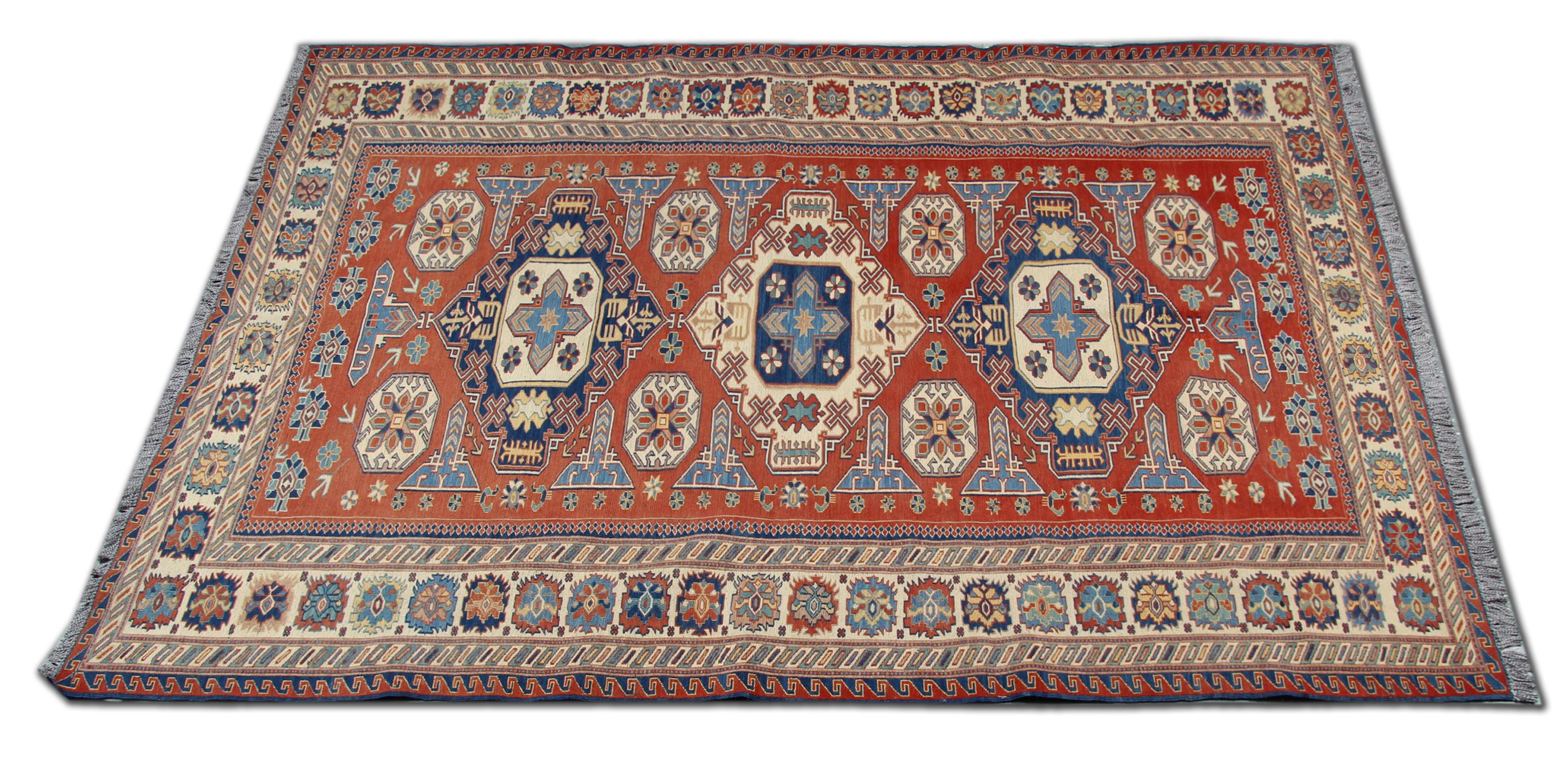 This piece was woven by hand in Afghanistan in 1950 with an elegant tribal medallion design in accents of cream and blue on a rust background. Woven with great intricacy in a symmetrical pattern, the central design is then framed by a repeat pattern