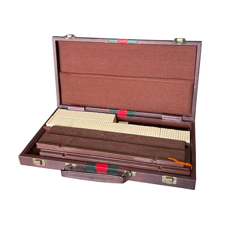 A vintage rummy set in a carrying case. This set includes card pieces that look like dominos and are in a faux leather Gucci-inspired carrying case. The set also comes with four stands for standing up the game pieces. This is a complete set. The