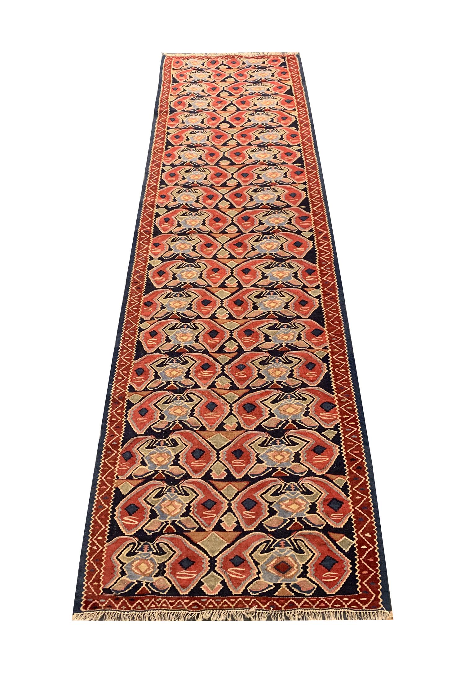 Dieser elegante flachgewebte Läufer ist ein hervorragendes Beispiel für kaukasische Kelims aus den 1950er Jahren. Das Design zeigt ein sich wiederholendes All-Over-Muster, das mit Akzenten in Rot, Beige, Blau und Grün gewebt ist. Das Design und die