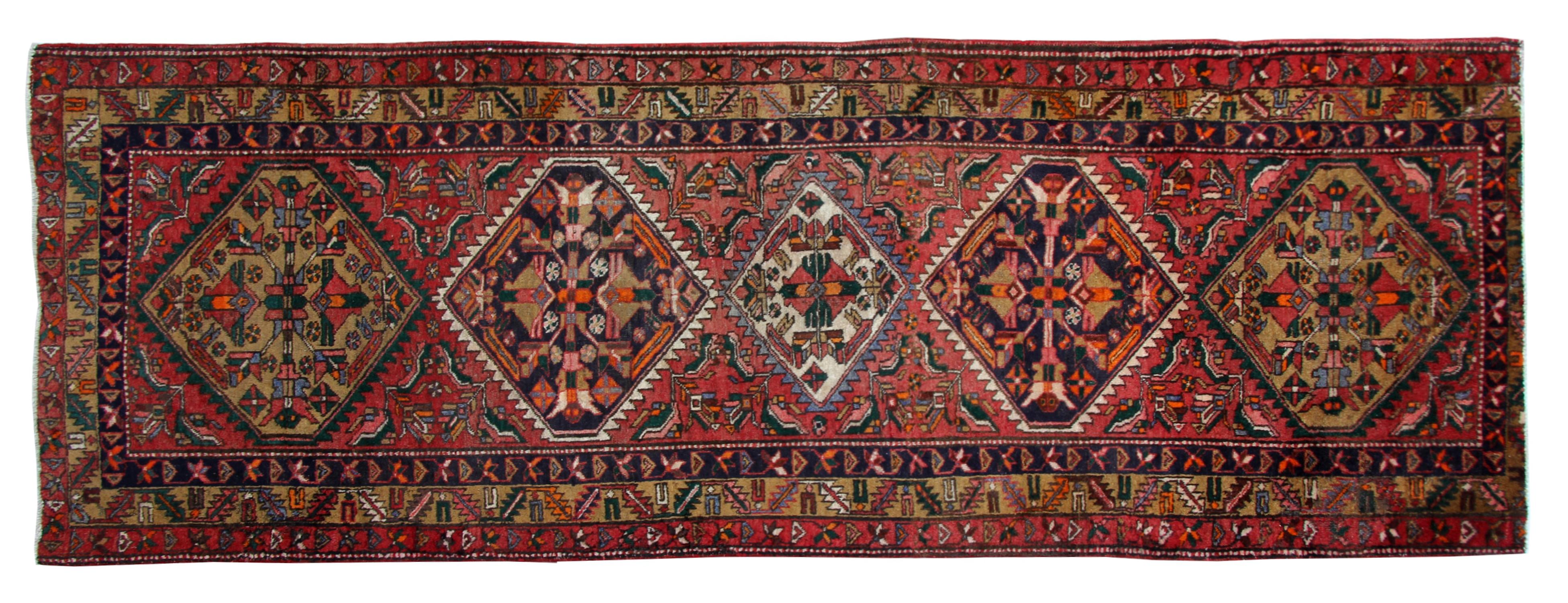 This fine wool runner rug is a fine example of vintage rugs from the 1960s. Constructed with a simple red cream colour palette. Then the repeat tribal floral design is woven in a deep blue background in brown, orange and ivory accents. A decorative