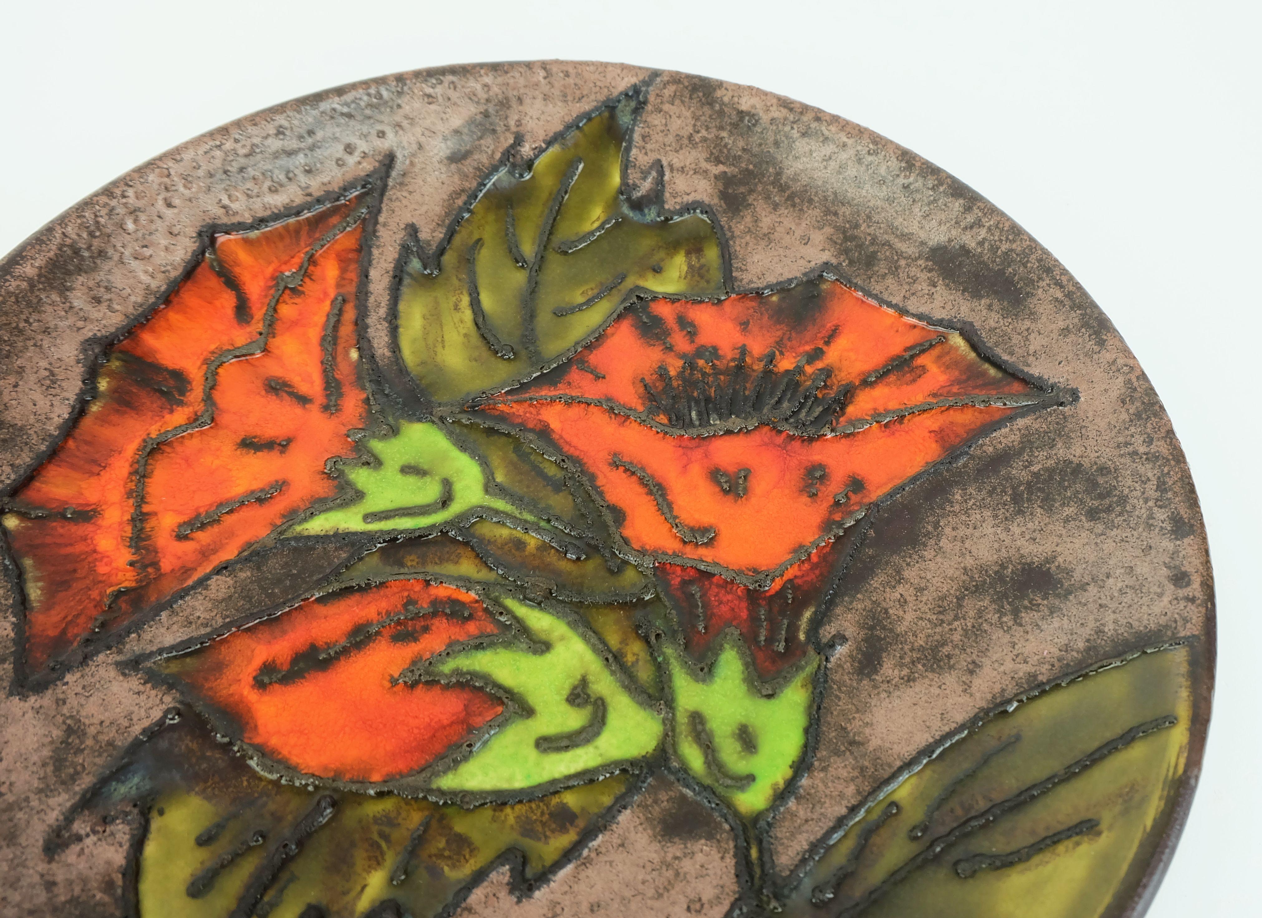 Plato de pared vintage que también puede utilizarse como frutero. Esmalte mate en distintos tonos de marrón y cobre combinado con una decoración floral en esmalte de lava grasa verde, rojo, naranja y negro. 

Dimensiones en cm:
Diámetro 28,5 cm,