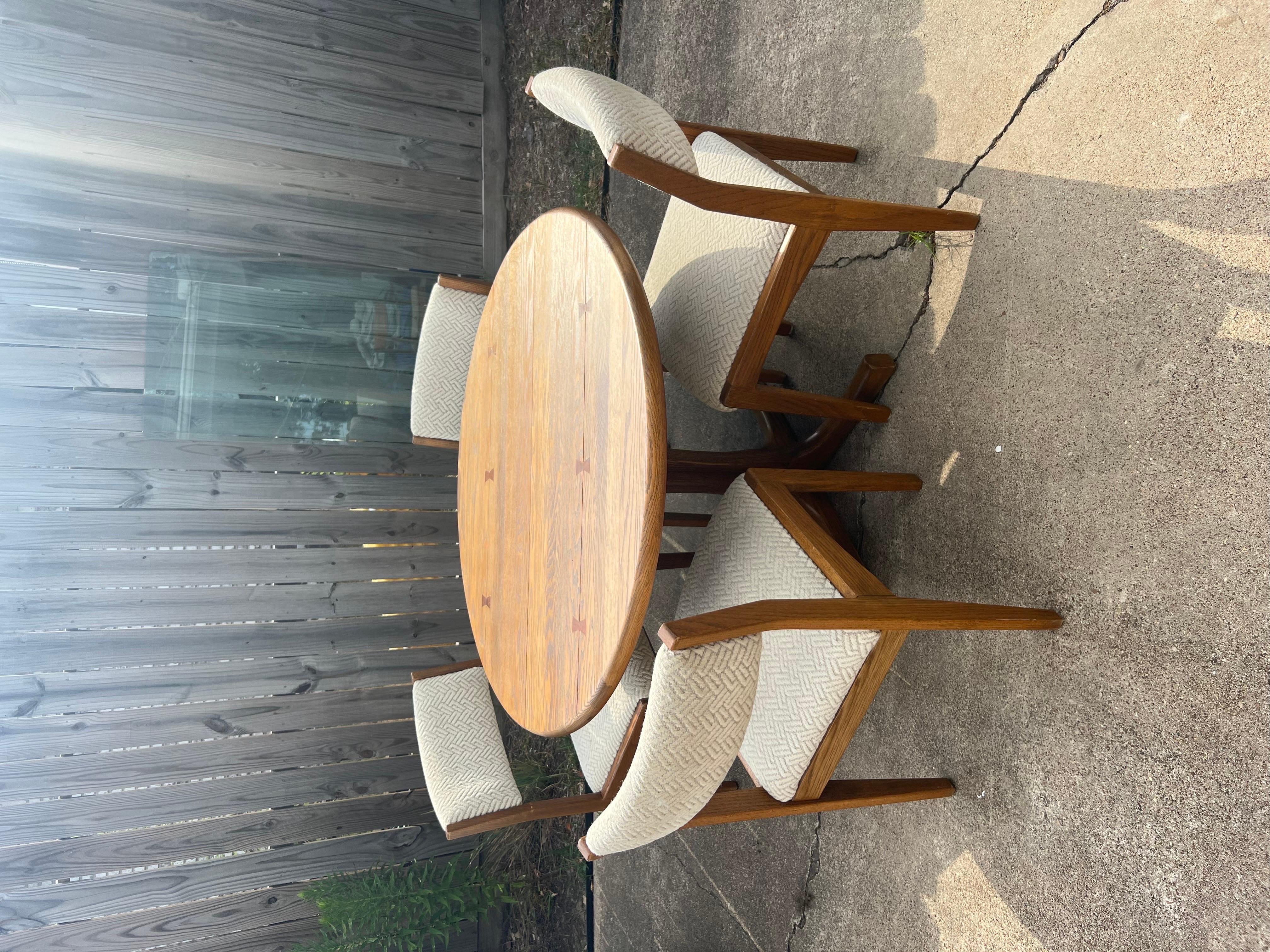 Vintage solid oak round pedestal dining table and 4 chairs by Conant Ball. Does not come with leaves. Fabric has some minor discoloration, and there is normal wear on the table from age. Everything is in its original condition.
