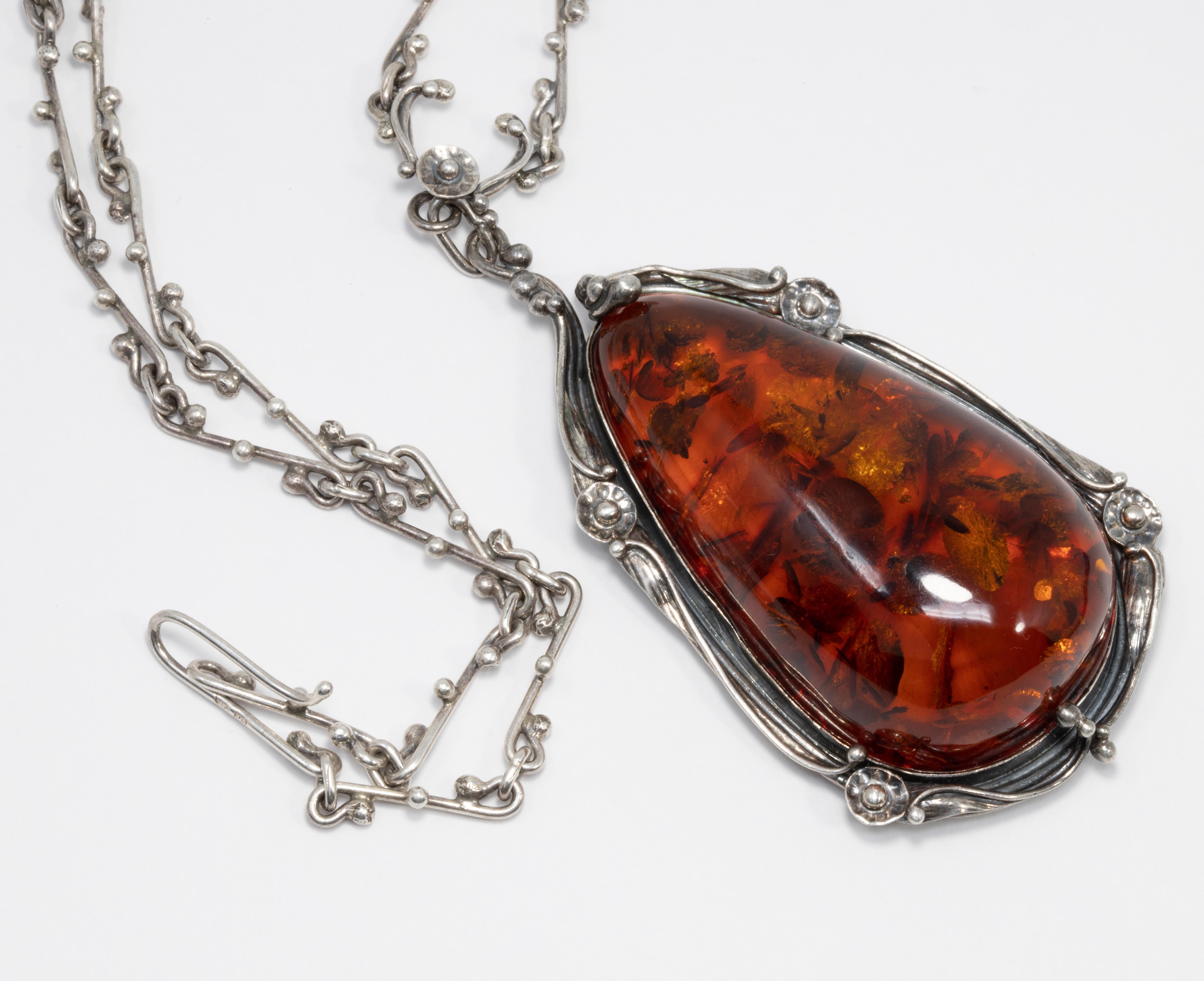 Exquisite Russian pendant, featuring a large, genuine, Baltic amber cabochon set in an ornate, open-back bezel on a stylish chain.

Sterling Silver.

Necklace length: 19.5 inches / 49.5 cm
Pendant dimensions: 2.7 x 1.6 in / 6.5 x 4.2 cm