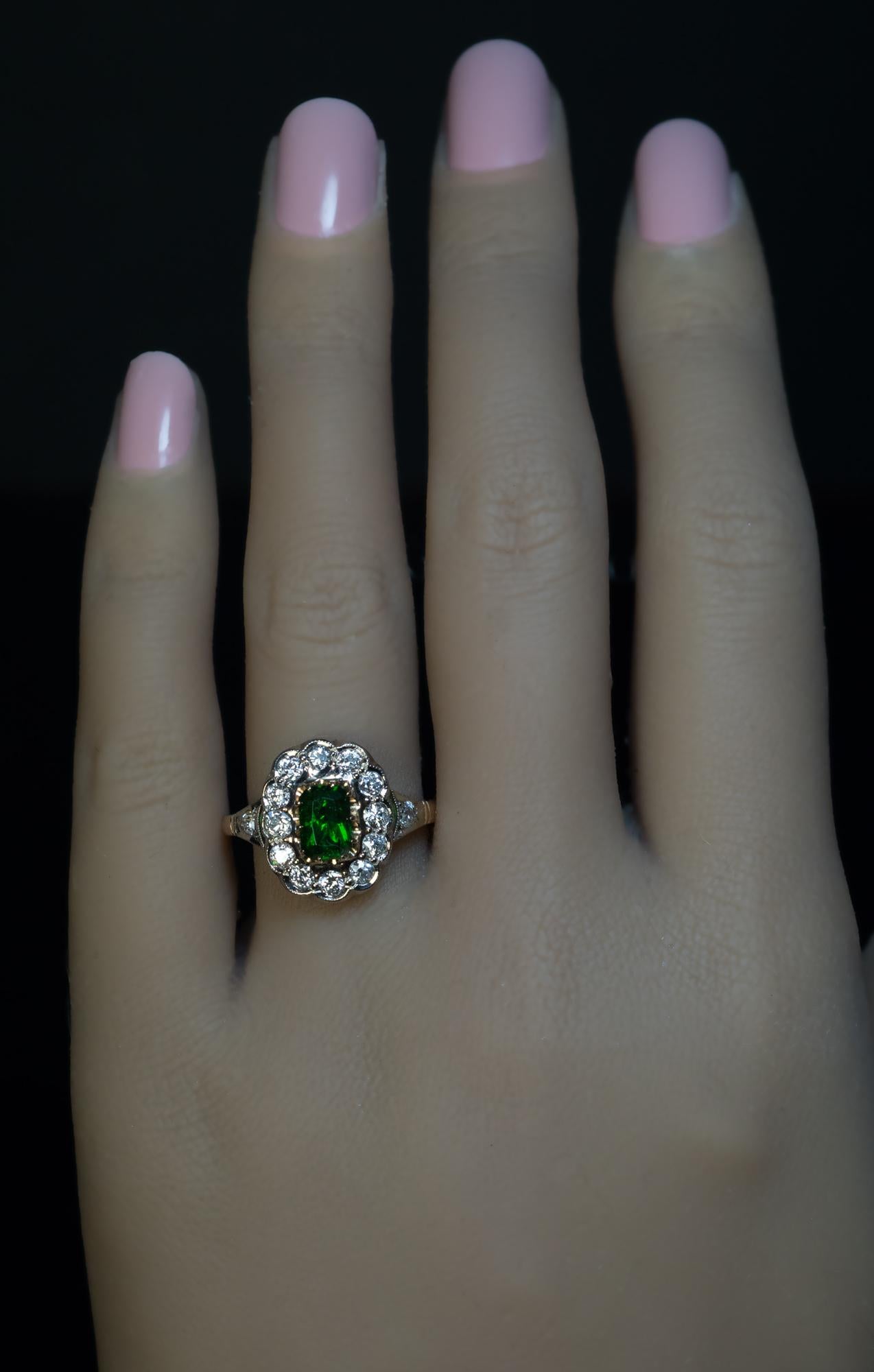 This vintage Russian cluster ring from the 1930s is crafted in white and yellow 14K gold. The ring features a modified emerald cut Russian demantoid from the Ural Mountains of a rare saturated alpine green color. The demantoid measures 6.9 x 4.7 x