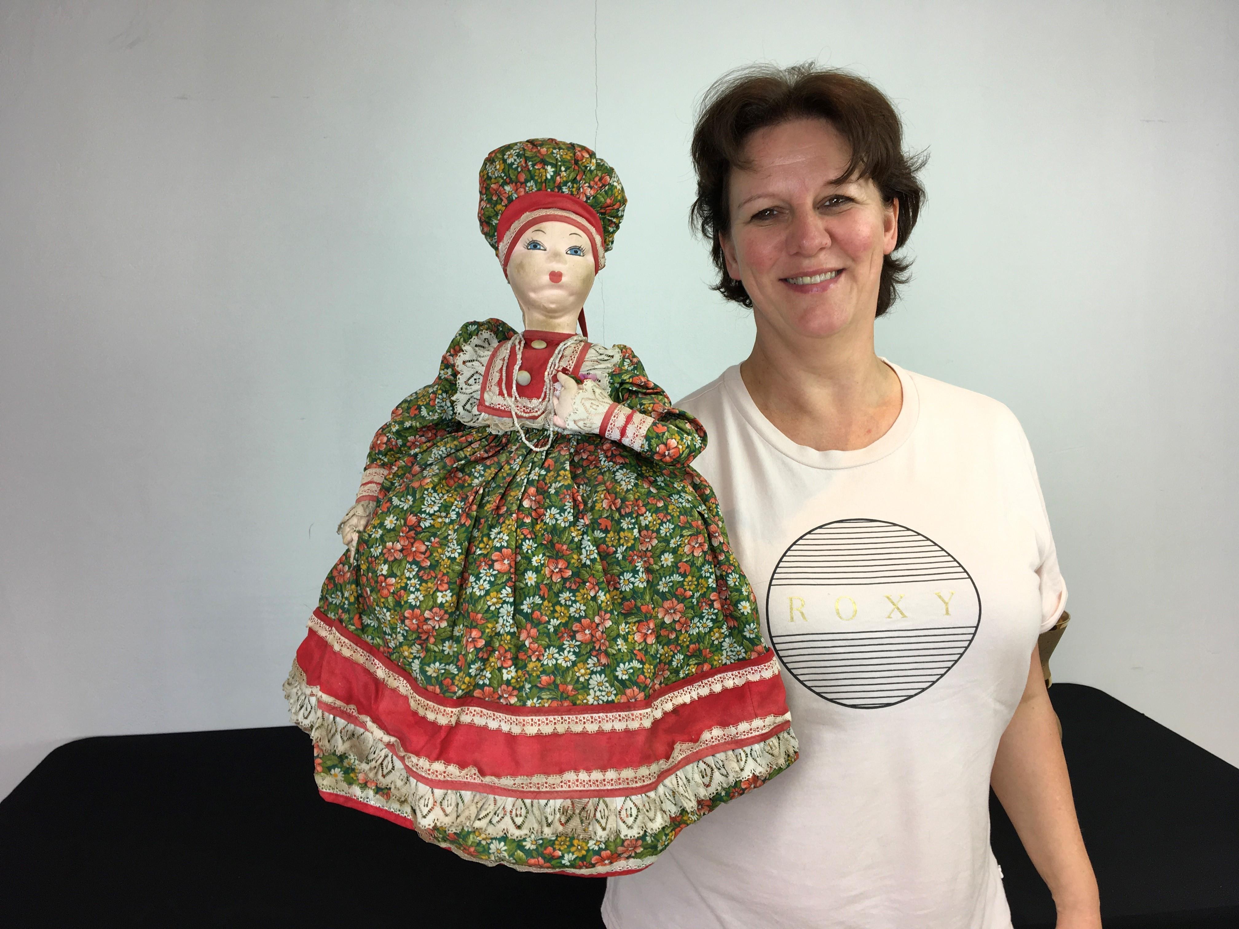 Vintage Russian samovar doll teapot cosy or samovar teapot cover. 
This large sized handmade doll has a molded fabric head with painted eyes, red lips and a large green dress with lots of flowers and lace finish. She's holding a bouquet of flowers