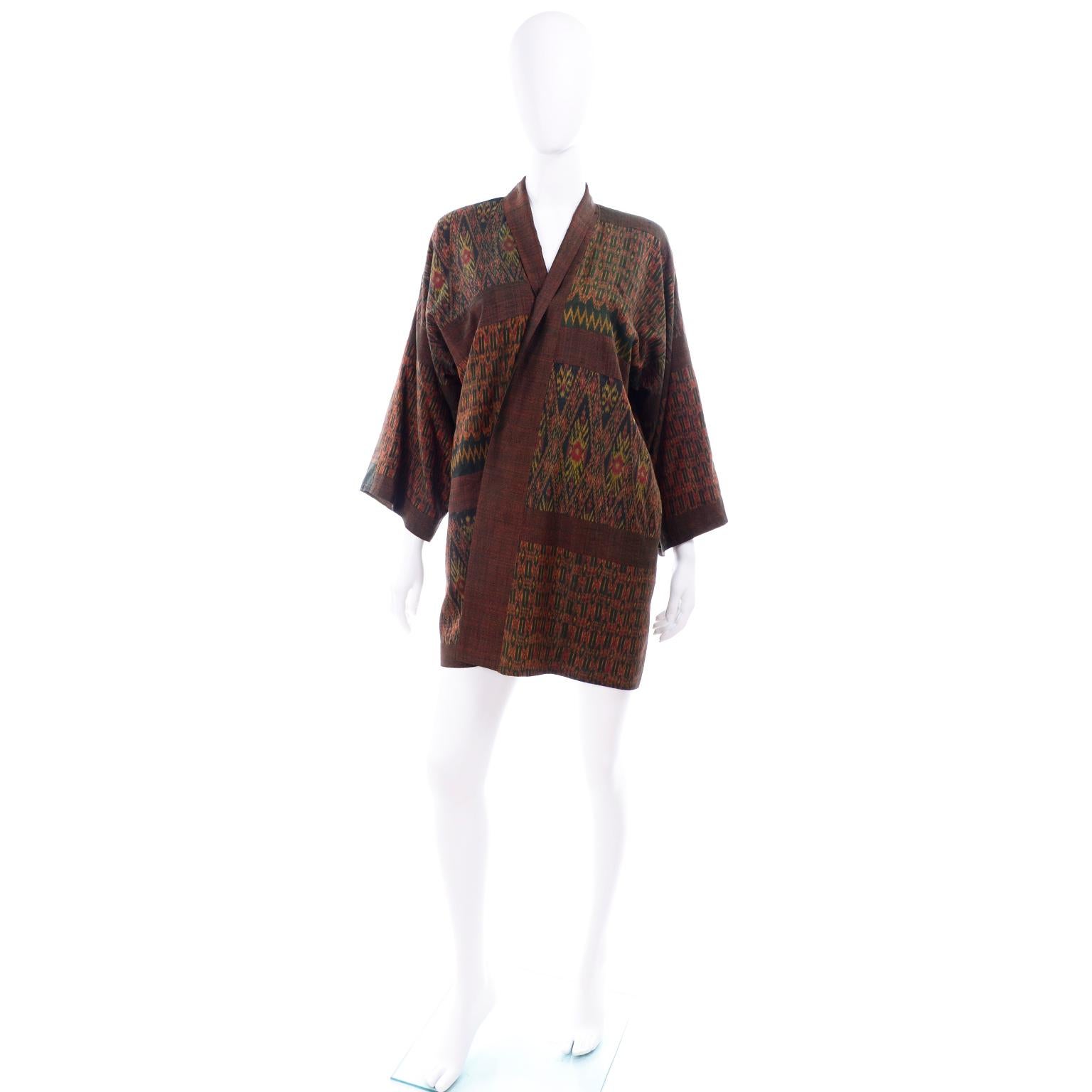 Diese Vintage-Seidenkimonojacke ist in kräftigen Herbsttönen wie Rot, Rost, Grün und Gold gehalten. Der Kimono hat gemischte Muster im Ikat-Stil und ist gefüttert  in braun. Auf der linken Brustseite befindet sich eine Innentasche und außen sind 2