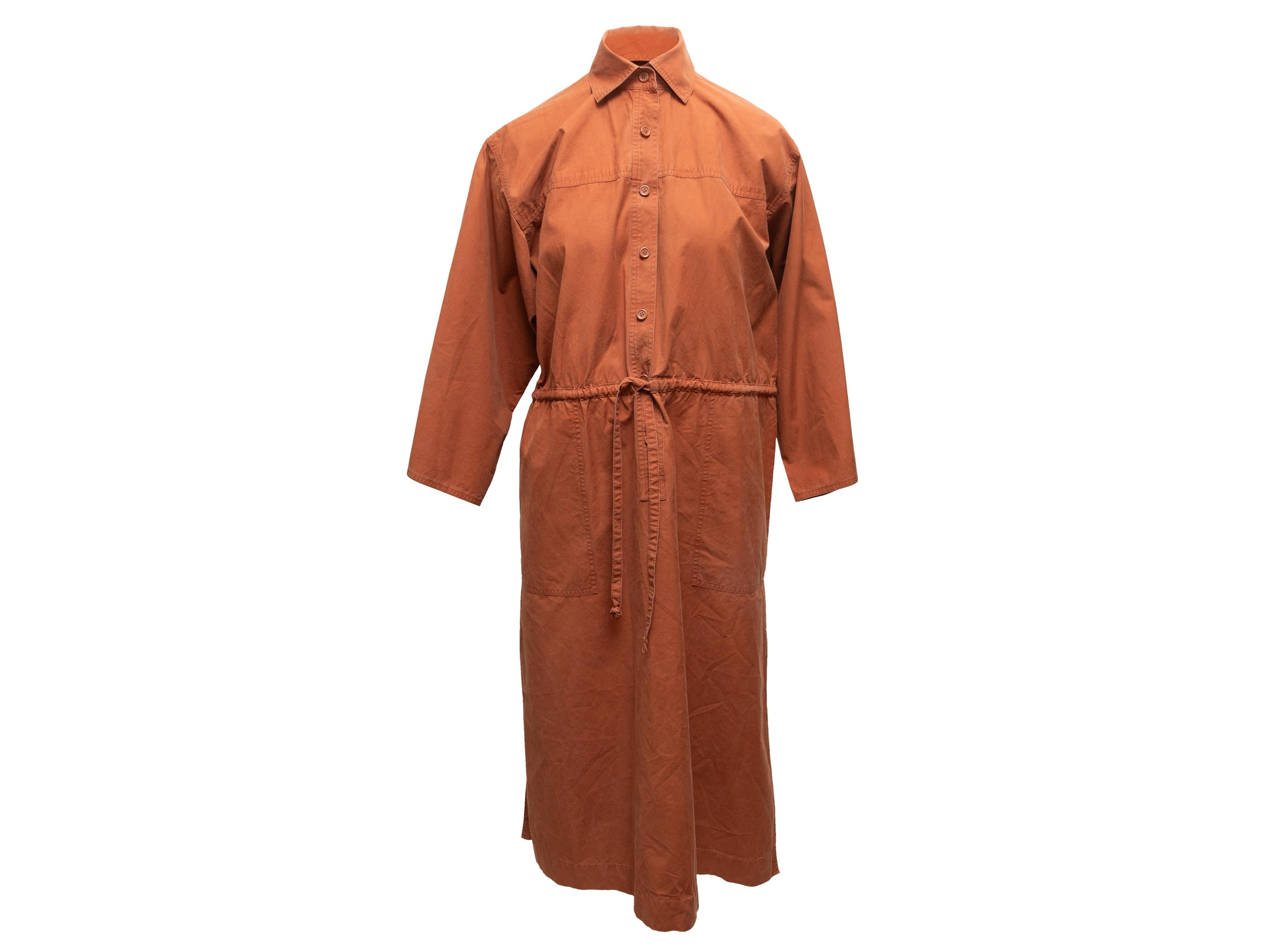 Vintage rust tunic dress by Saint Laurent. Circa 1978. Pointed collar. Long sleeves. Dual hip pockets. Drawstring at waist. Button closures at front. 40