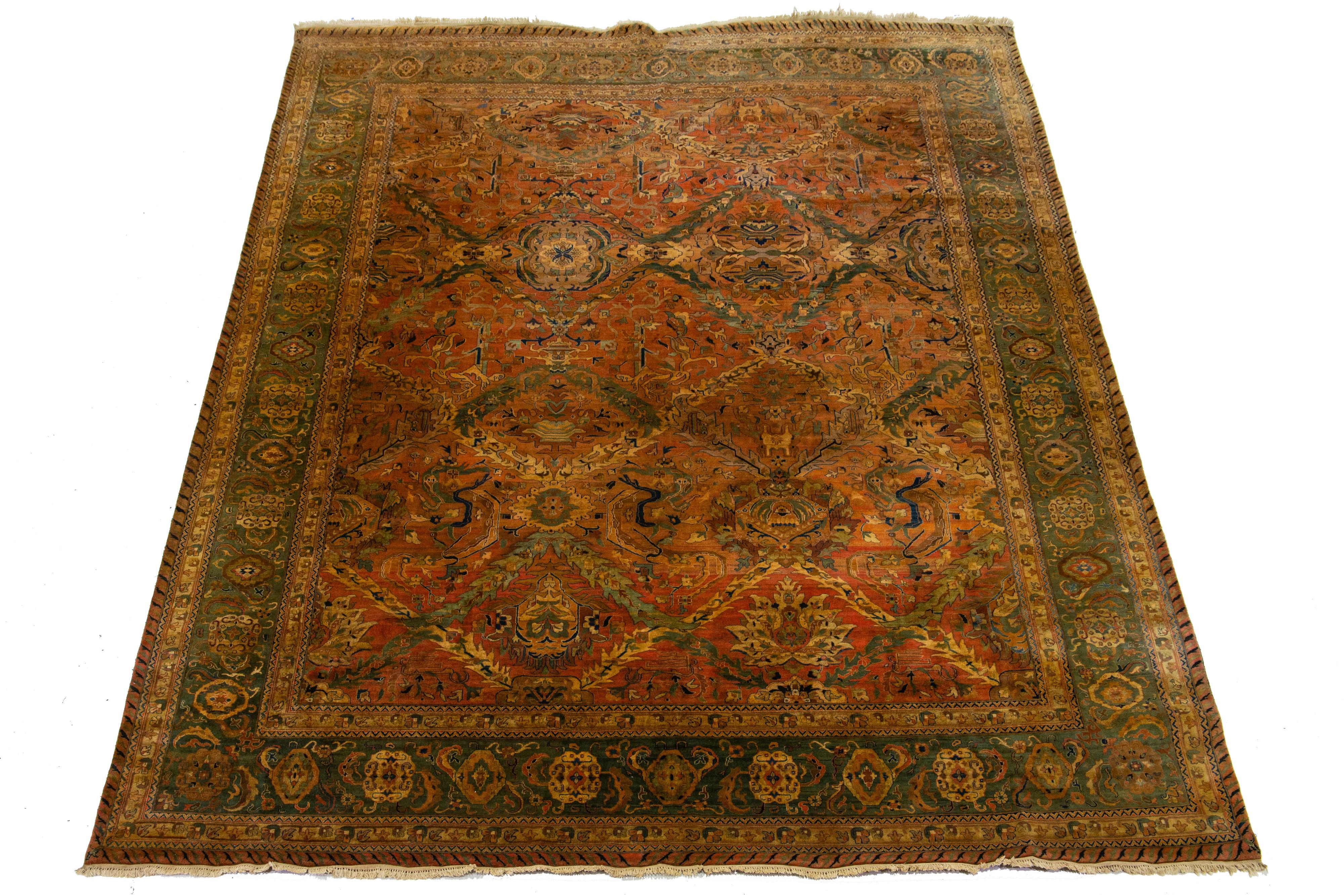 Beautiful antique Persian hand-knotted wool rug with a rust color field. This piece has a green frame with golden-beige, blue, and green accents in a gorgeous all-over floral design.

This rug measures 12' x 16'2