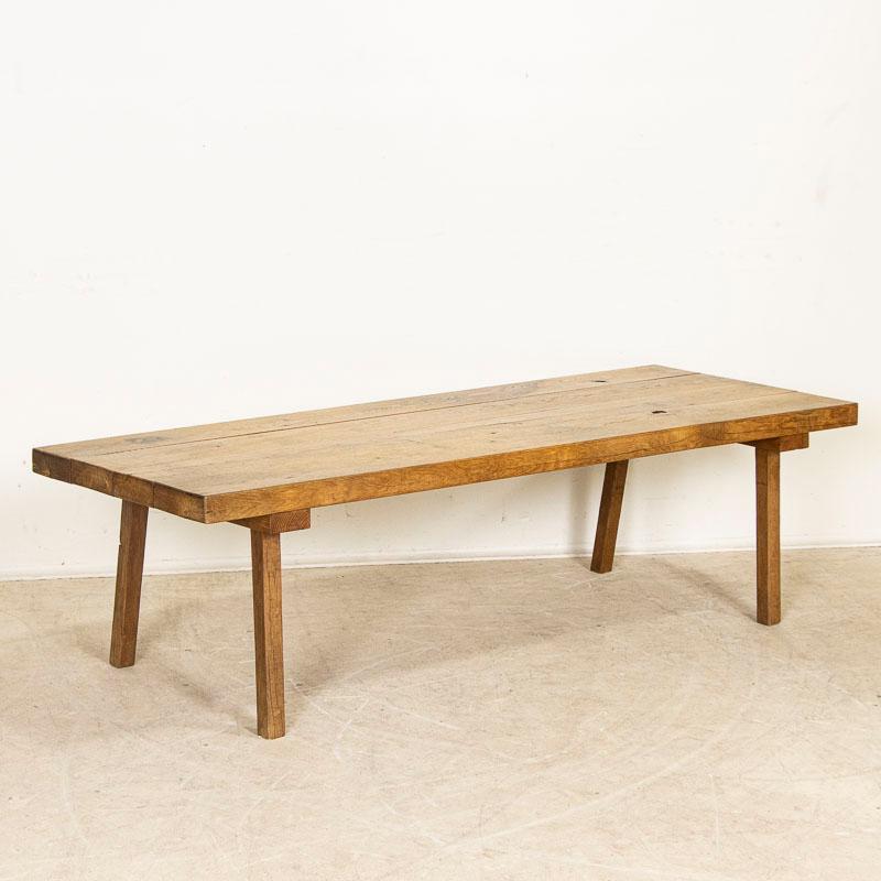 There is something organic and inviting in the plank hard wood top of this rustic peg leg coffee table. At almost 6' long, it is a fun find. It is the years of use that have deepened its character, with a wonderful worn patina grown richer over