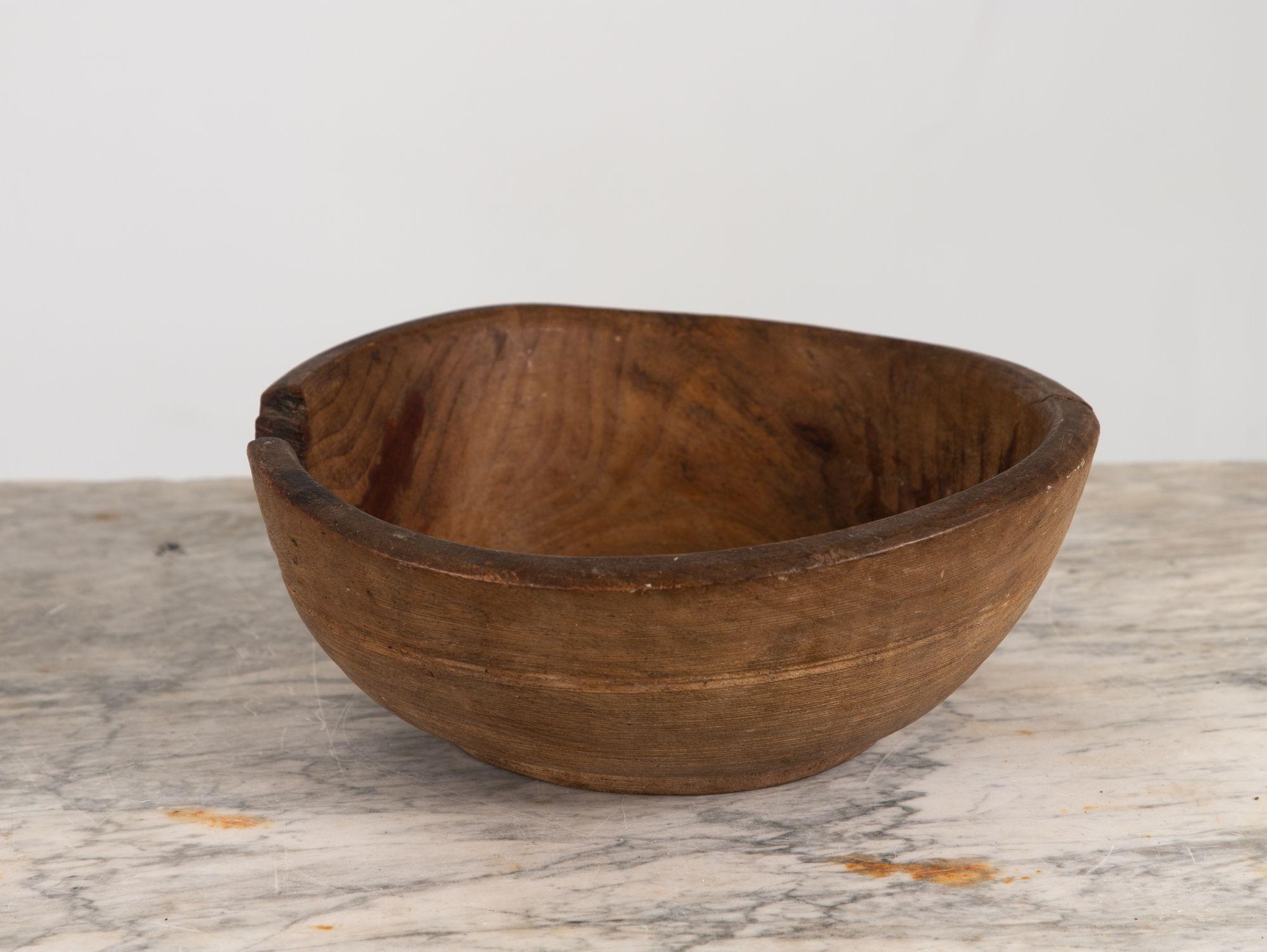 This vintage dugout wood bowl is a remarkable piece that embodies rustic charm and history. Crafted from a solid piece of wood, it showcases the natural beauty and unique grain patterns of the material. The bowl's dugout design suggests it was