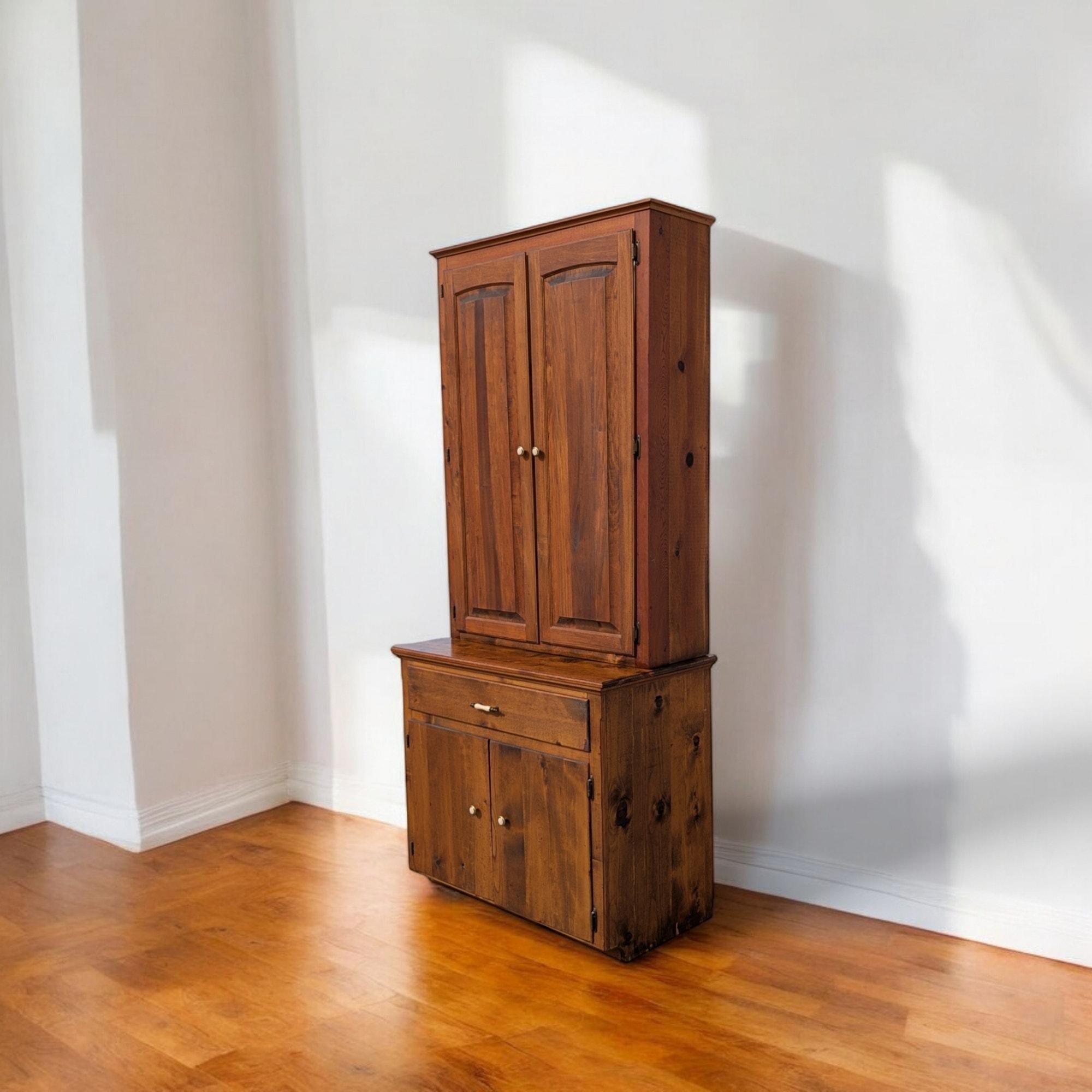 Charming mid-20th-century American Country pine hutch, handcrafted in solid knotty pine with warm honey-toned finish. The upper cabinet features double paneled doors that open to adjustable shelving, ideal for displaying pottery, glassware, or
