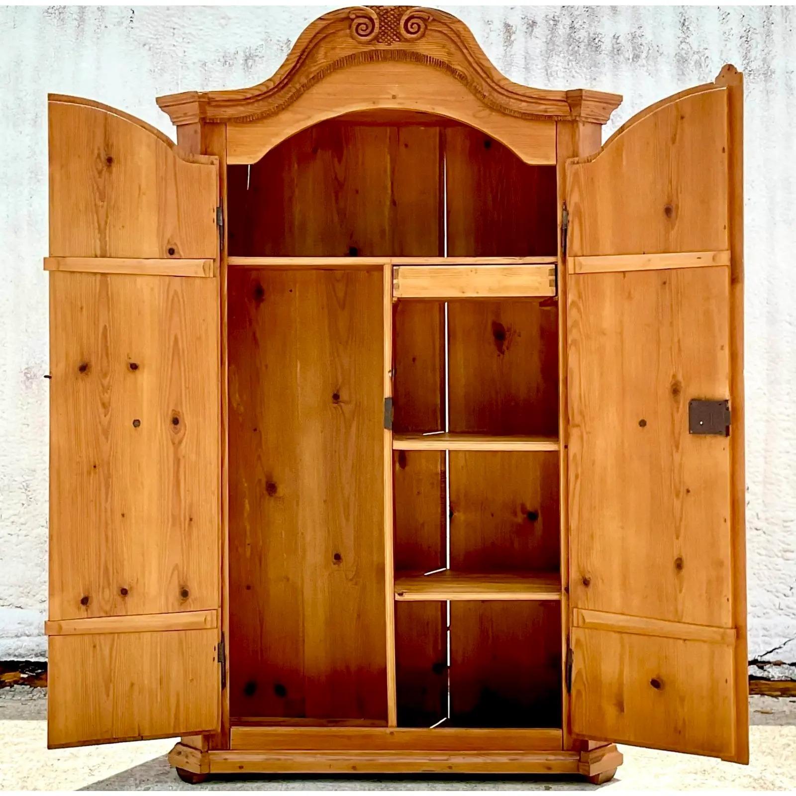 A fabulous vintage Rustic pine armoire. Beautiful hand carved detail on front. A high arched top with additional carvings. Beautifully laid out interior with areas for hanging and shelving. Acquired from a Palm Beach estate.