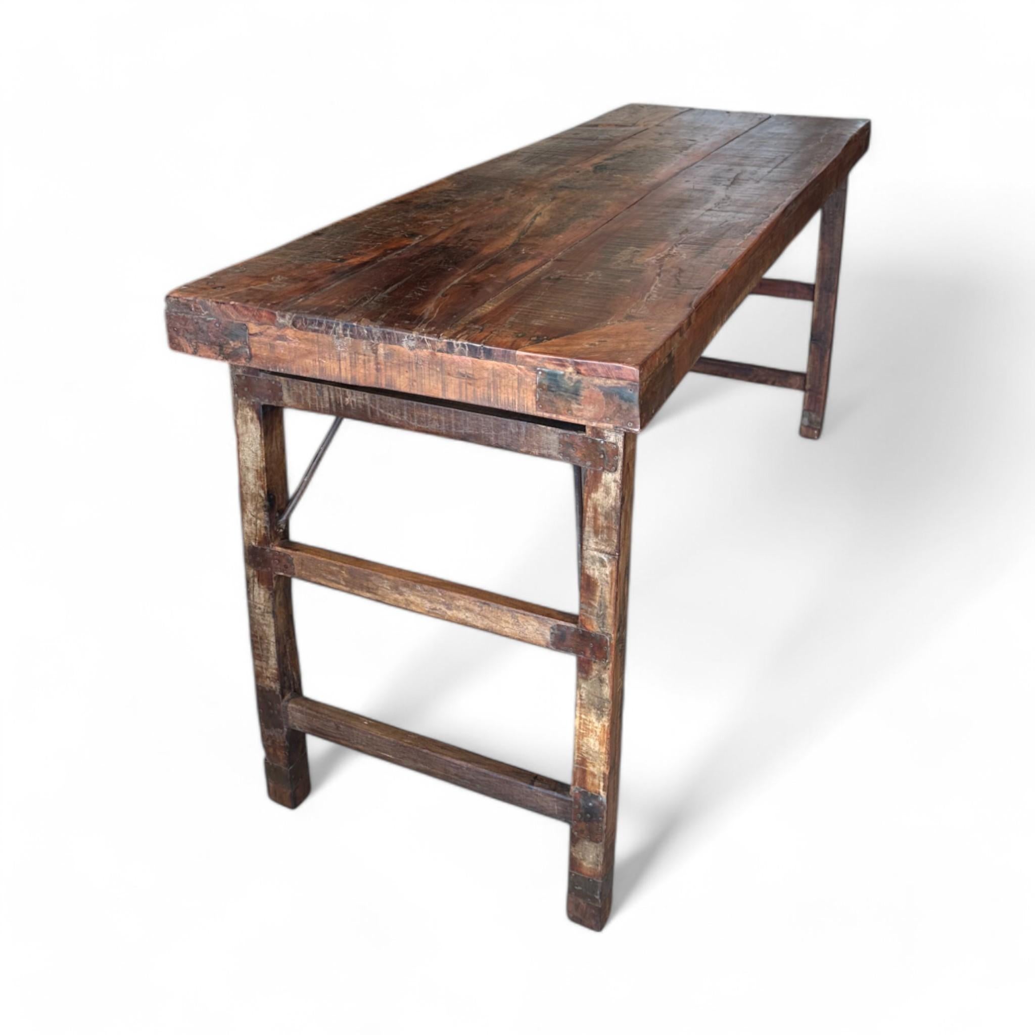 Esta consola vintage tiene una superficie de madera rústica con una hermosa pátina envejecida, que desprende un encanto atemporal. Su diseño robusto la hace perfecta para usarla como mesa expositora o escritorio compacto en cualquier espacio. Una