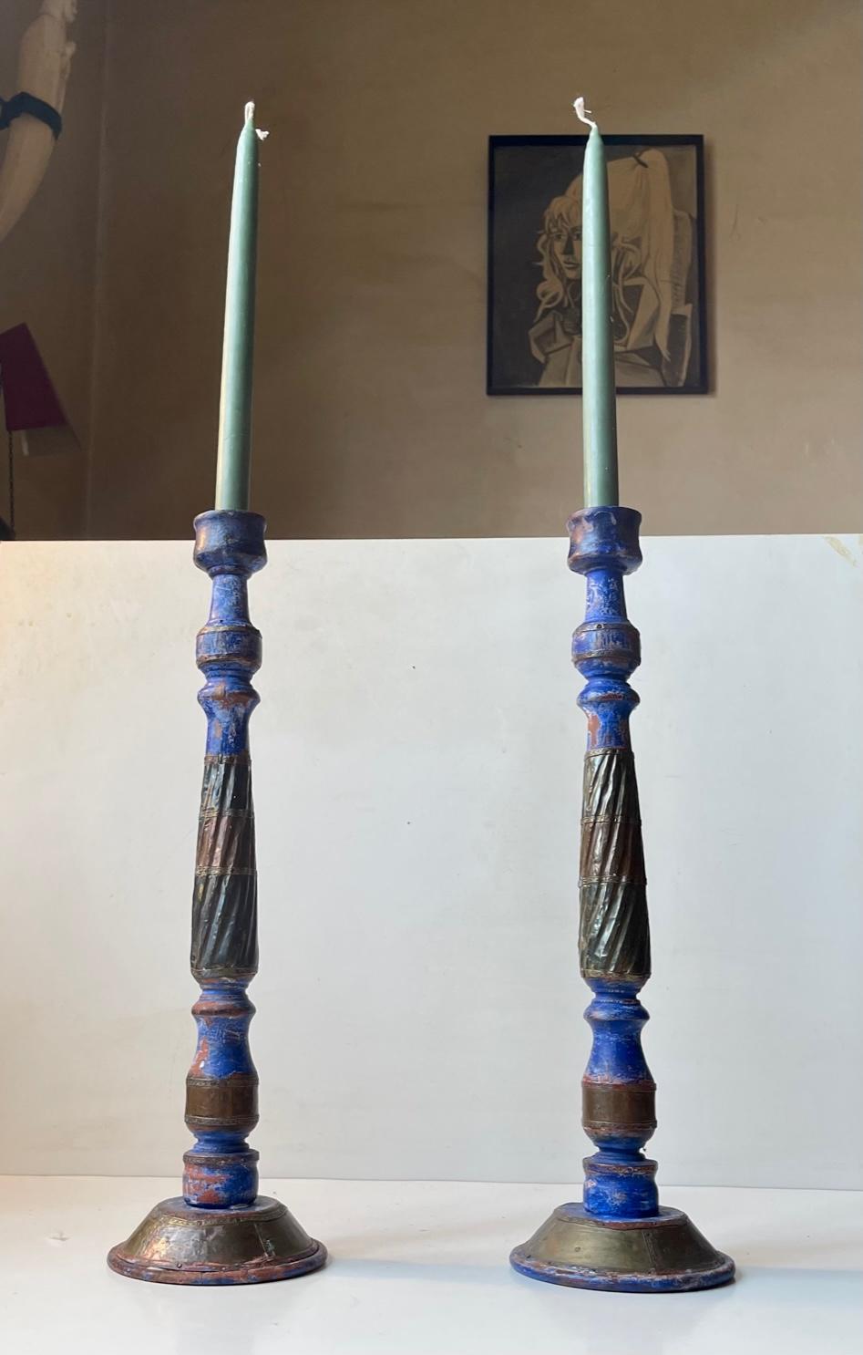 Decorative pair of large wooden candleholders in rustic paint and partially dressed with mixed metals. Probably made in Asia circa 1970-90. They are to be fitted with regular sized candles. Measurements: H: 42 cm, Diameter: 12 cm (base).