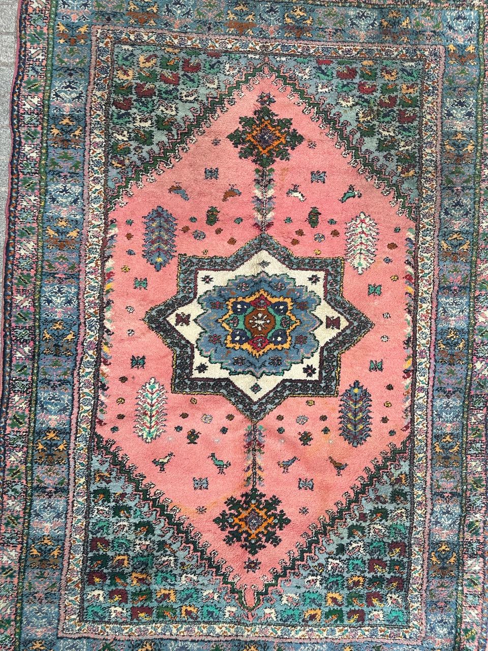 Bellissimo tappeto marocchino di metà secolo con un disegno geometrico e tribale con medaglione centrale e fiori stilizzati e un campo rosa con verde, arancione, viola, blu, marrone, azzurro e nero, interamente annodato a mano con velluto di lana su
