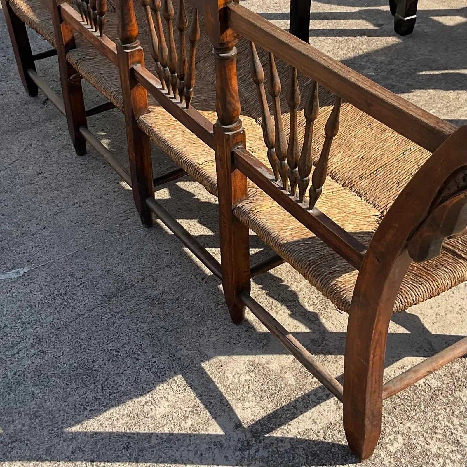 A fantastic vintage Boho rush seat long bench. A wide profile with exaggerated scroll arms and harvest spindles. Acquired from a Palm Beach estate.