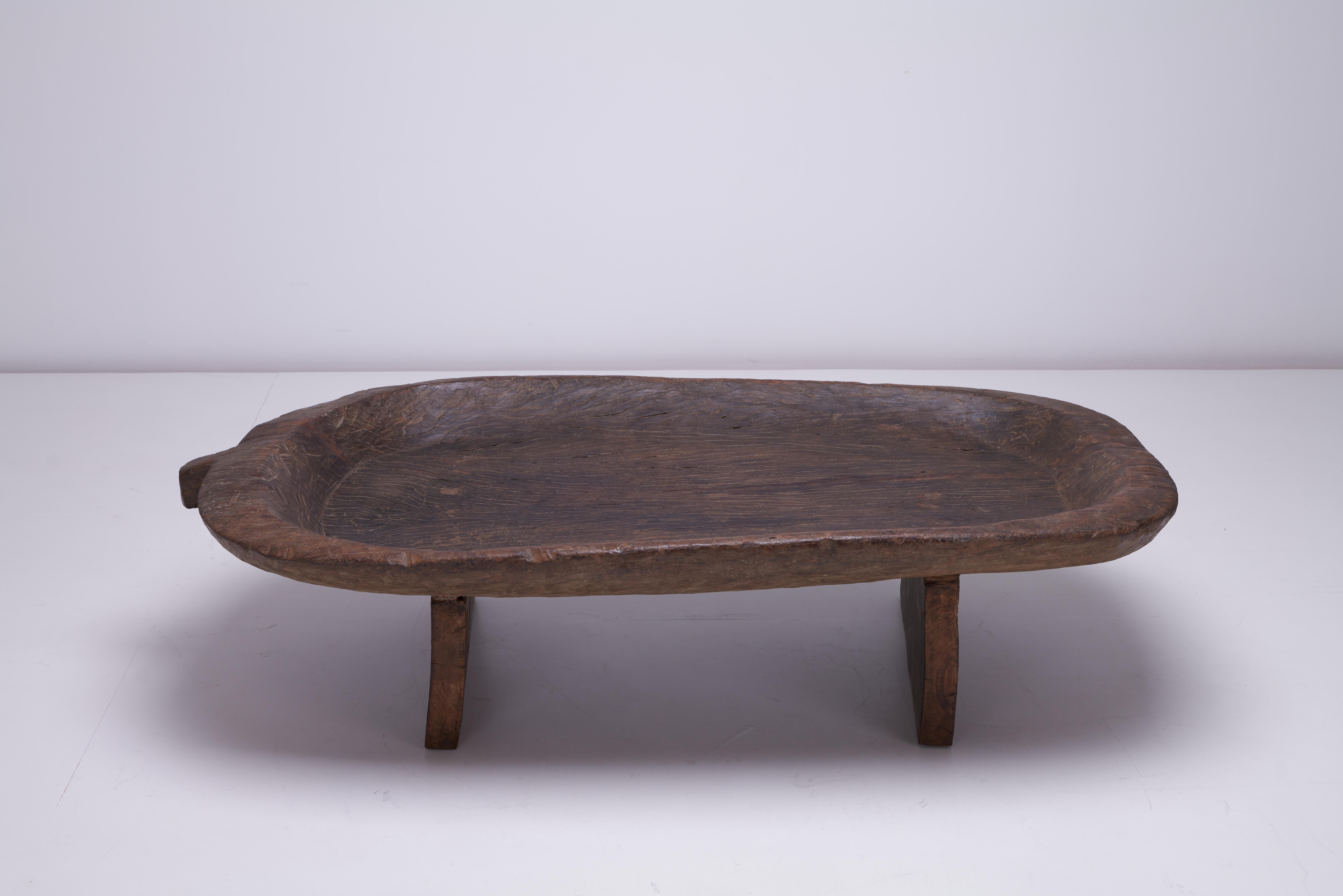 Tenemos a la venta una mesa utilizada para secar grano procedente de la zona tribal del NE de la India, Nagaland. La parte superior está tallada en una sola pieza de madera maciza de Hollock. En uno de los lados hay un asa que se habría utilizado