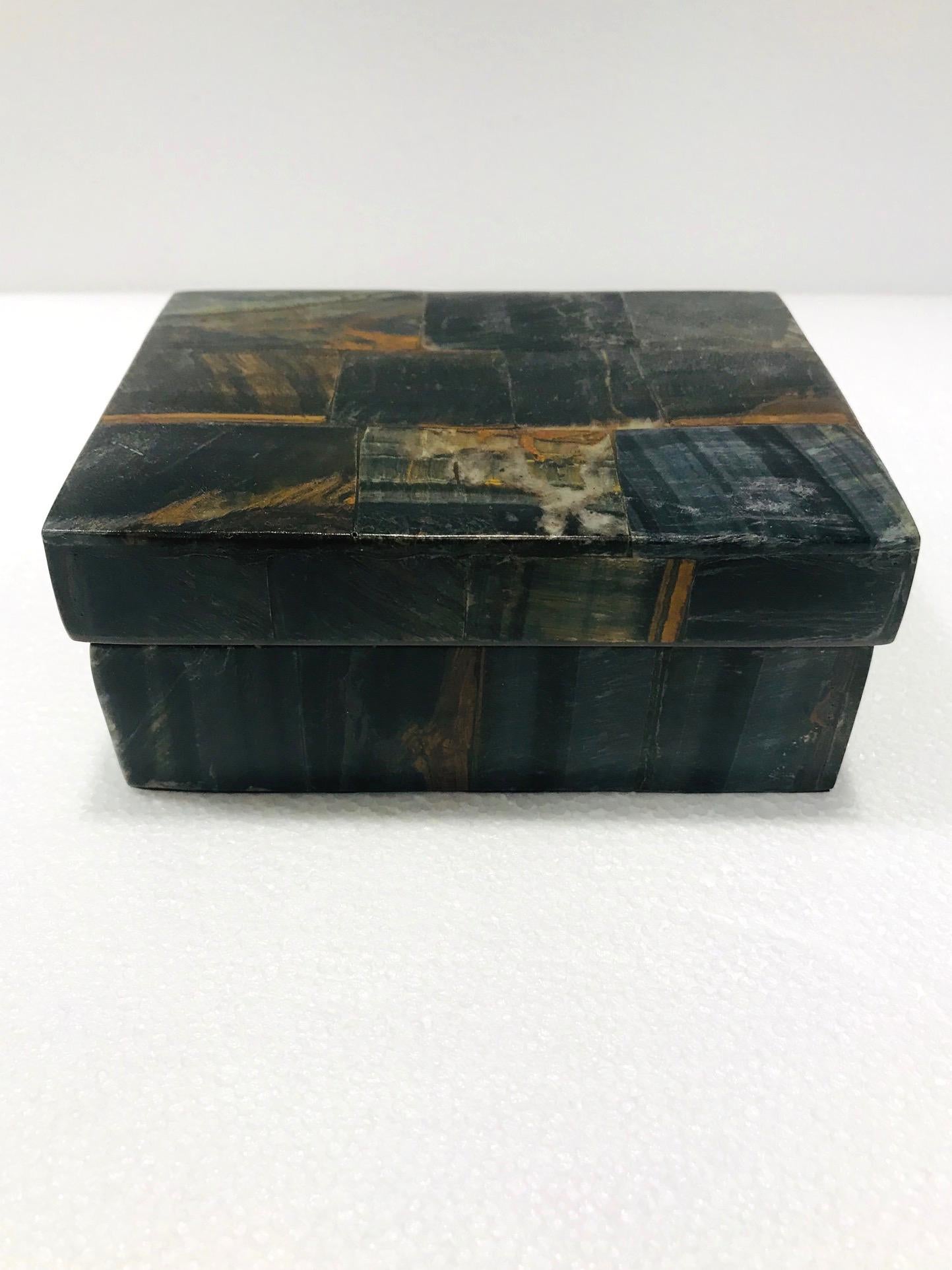 Organic Modern decorative box in semi-precious blue tiger eye stone, also known as falcon's eye. Tessellated design featuring inlays of multicolored stone in hues of brown, black, blue, rust, and dark green. Interior box is made of palm wood. All