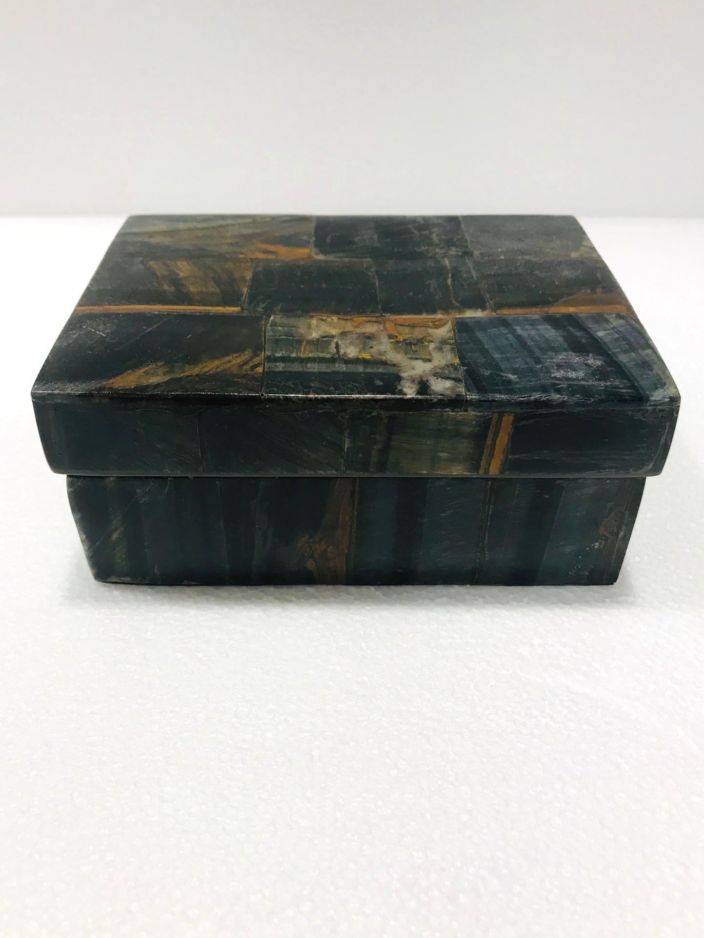 Organic Modern decorative box in semi-precious blue tiger eye stone, also known as falcon's eye. Tessellated design featuring inlays of multicolored stone in hues of brown, black, blue, rust, and dark green. Interior box is made of palmwood. All