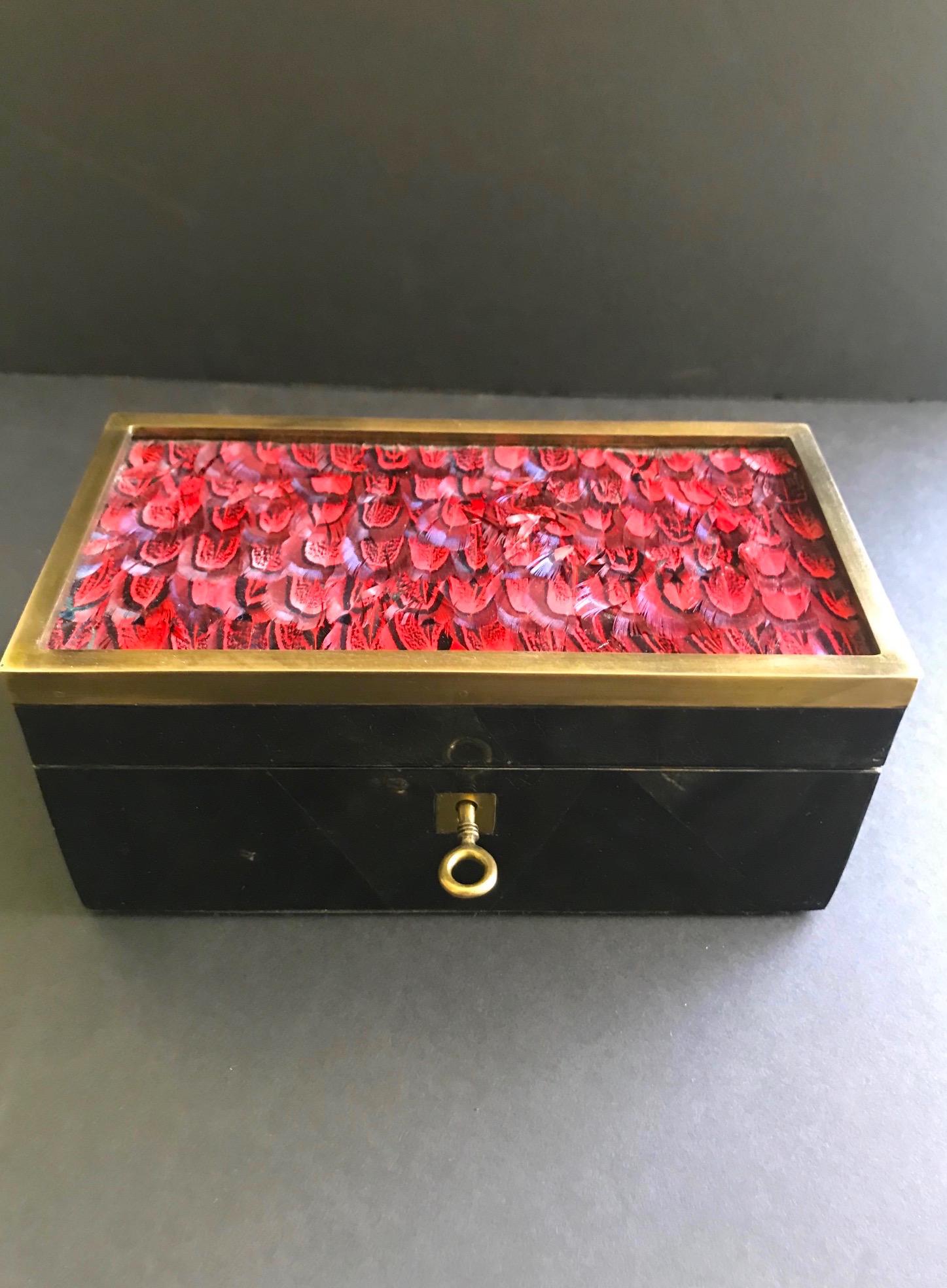 Exquisitely handcrafted decorative box or jewelry box. Comprised of lacquered pen shell with geometric mosaic patterns in hues of black. Box has bronze trim accent and exotic bird feathers in vibrant red. Fitted with bronze mount and key, and