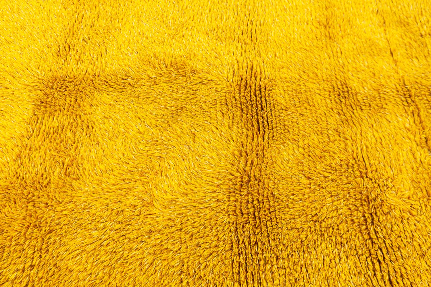 This is a vintage Rya carpet woven in Sweden during the mid-20th century circa 1950 - 1970s and measures 204 x 145CM in size. This carpet has a simplistic design comprised of no motifs and is made using a bright yellow background color. This piece