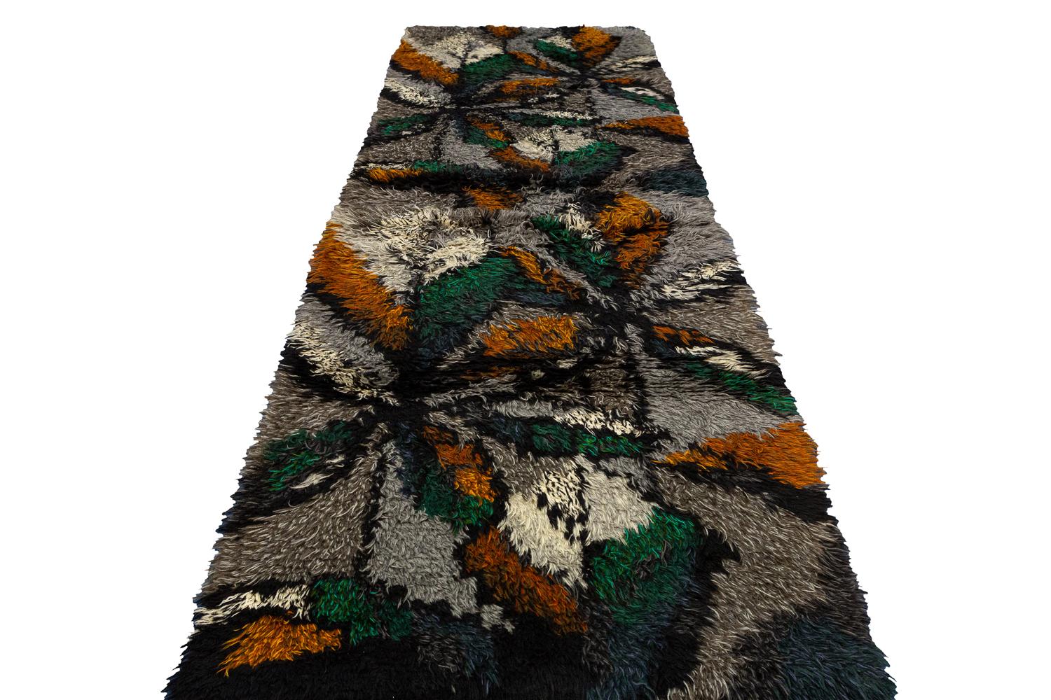 This is a vintage Swedish Rya runner woven during the mid-20th century circa 1950 – 1970’s and measures 334 x 115 cm in size. This runner is designed with large-scale plants with multi-colored pedals set on a gray background color. It has been woven