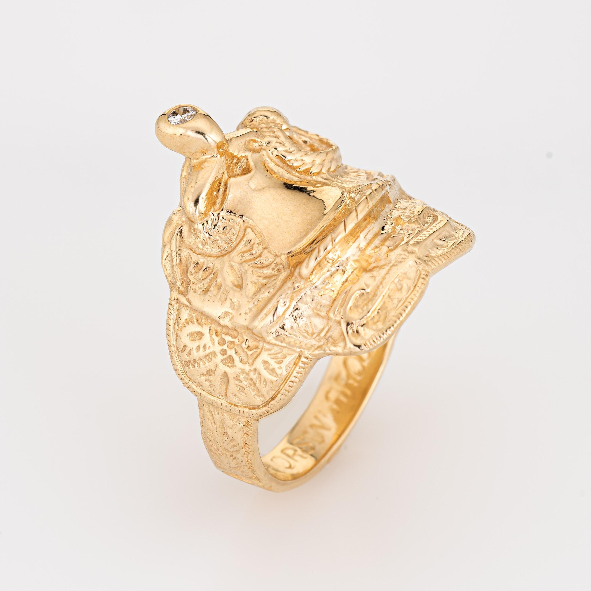Stylish vintage saddle ring (circa 1970s) crafted in 14 karat yellow gold. 

One round brilliant cut diamond is estimated at 0.05 carats (estimated at H-I color and SI1-2 clarity). 

The beautifully detailed saddle features etched foliate detail
