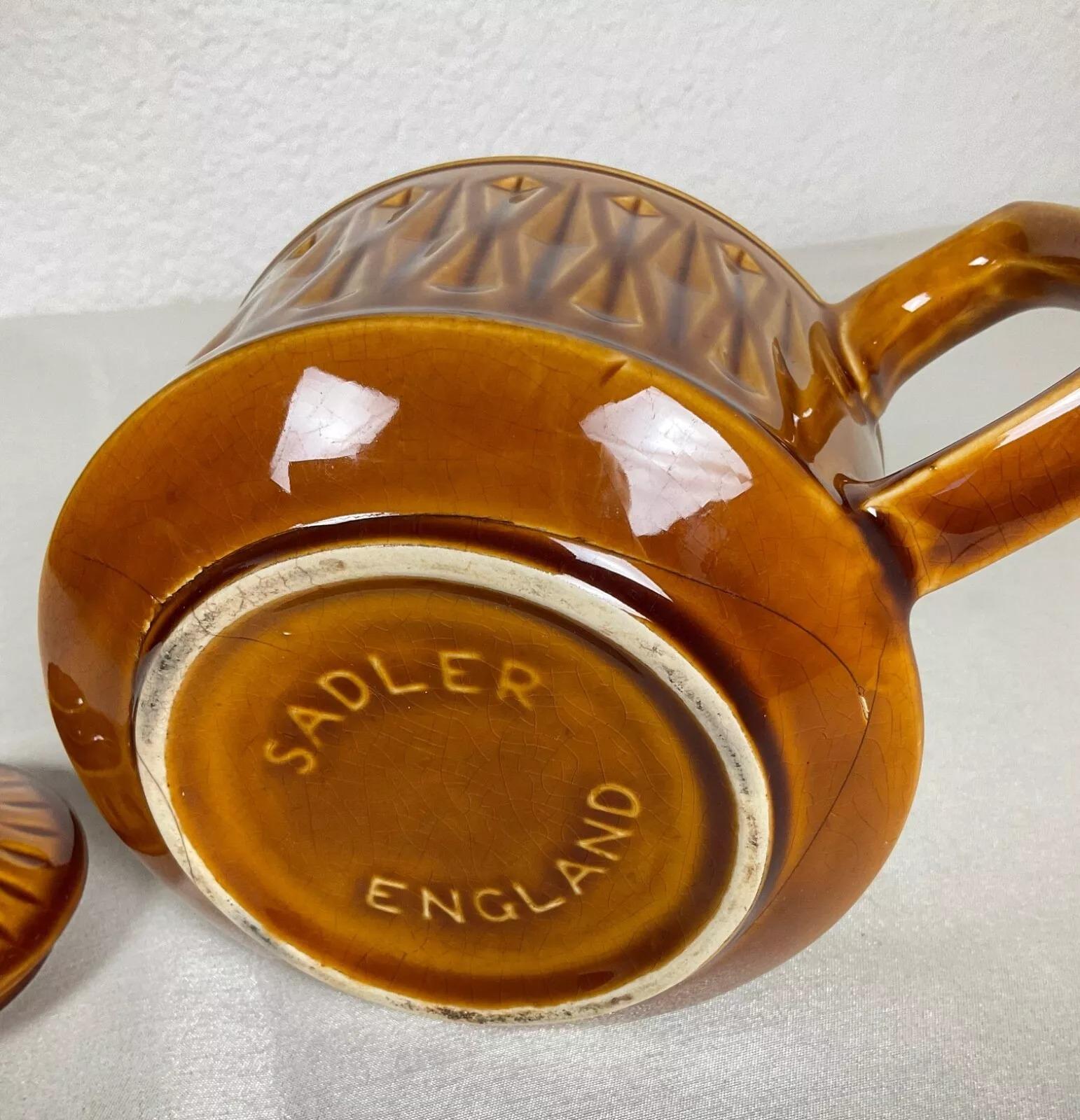 This vintage Sadler England teapot in brown ceramic is a delightful example of traditional English craftsmanship. Measuring 4.9 inches (12.5 cm) in height, 8.7 inches (22 cm) in length, and 5.5 inches (14 cm) in diameter, this elegant teapot weighs