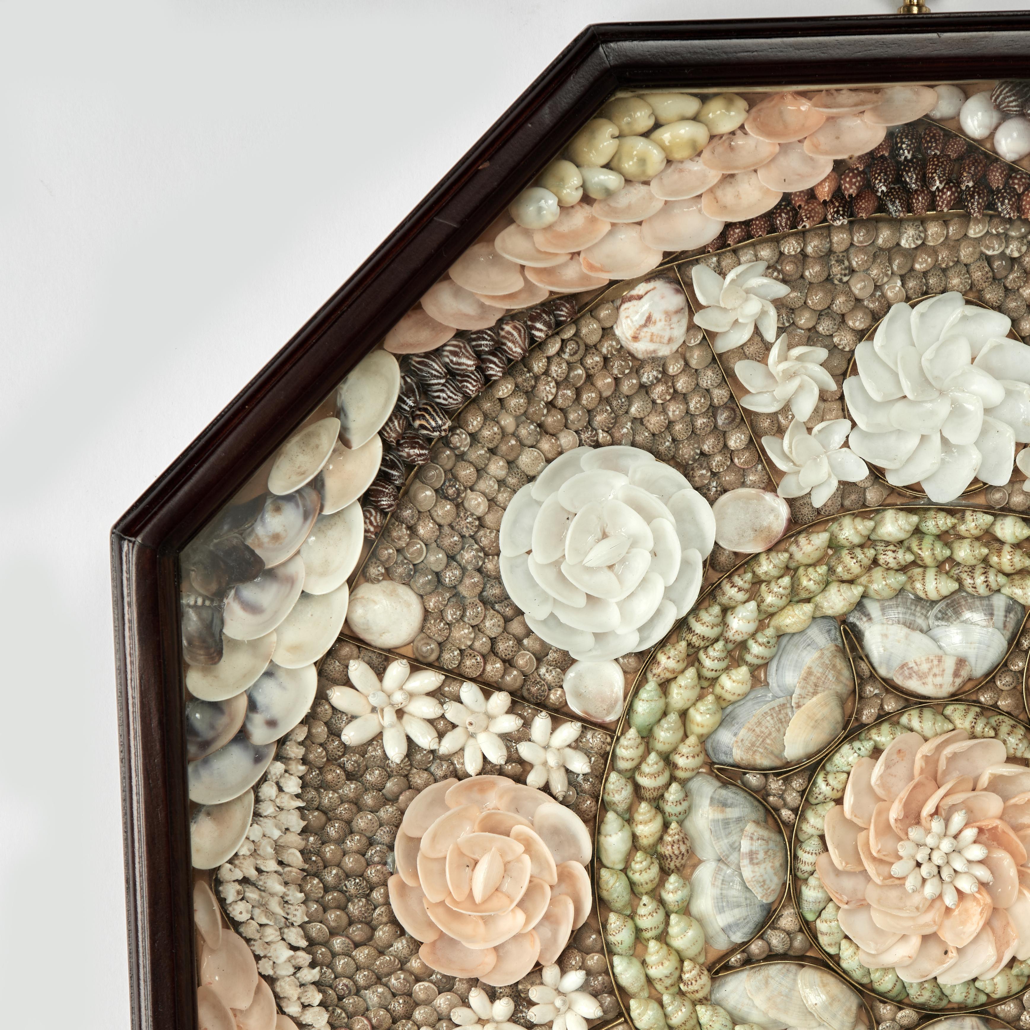 Un elegante San Valentino dei marinai vintage realizzato a mano con conchiglie organiche esotiche e ambiziosamente composto da un fiore come medaglione centrale all'interno di diversi bordi floreali disposti. Presentato sotto vetro in una scatola