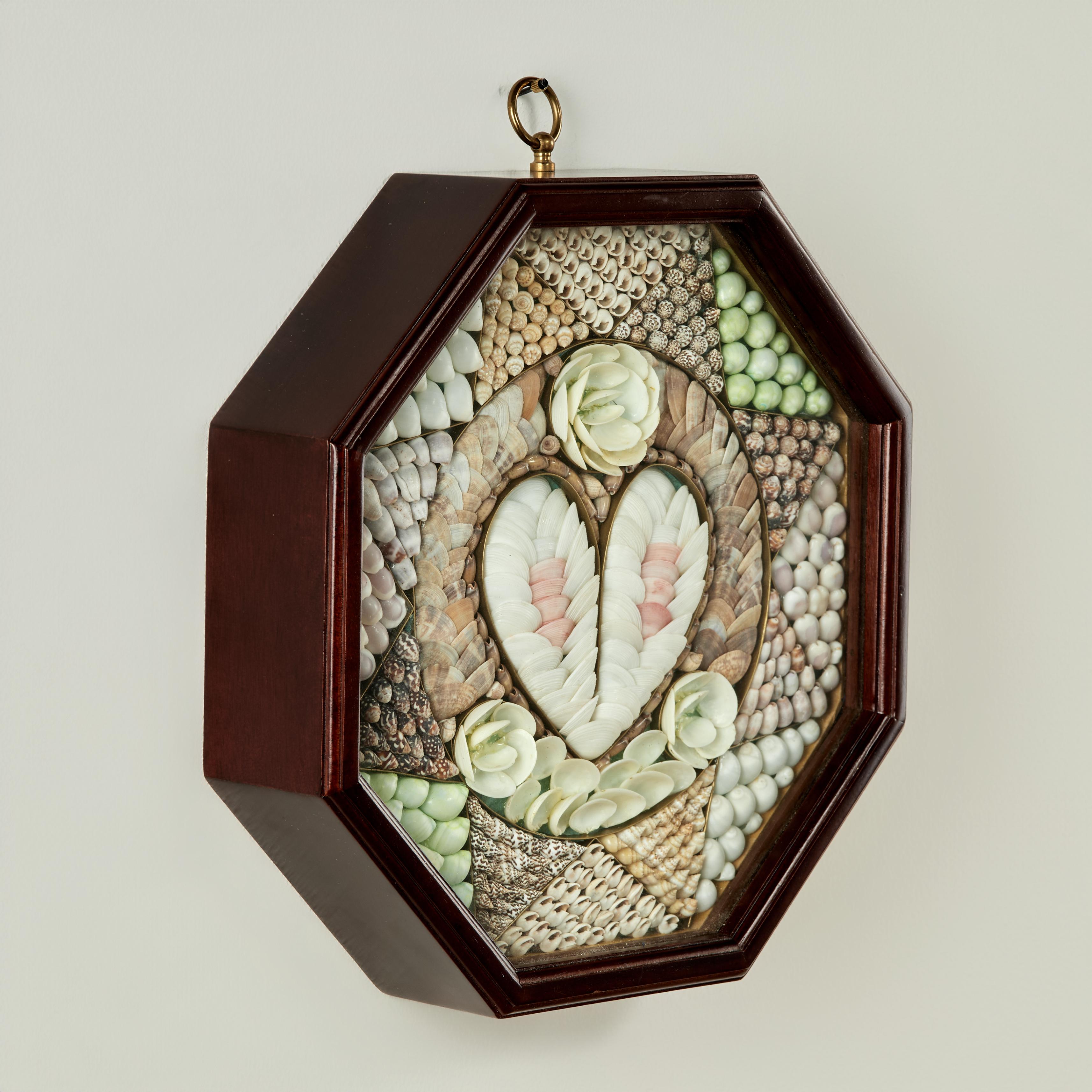 Encantadora tarjeta de San Valentín marinera de época, ambiciosamente elaborada a mano en exóticas conchas marinas orgánicas, con un motivo central en forma de corazón rodeado de compartimentos en forma de estrella. Presentada bajo cristal en una