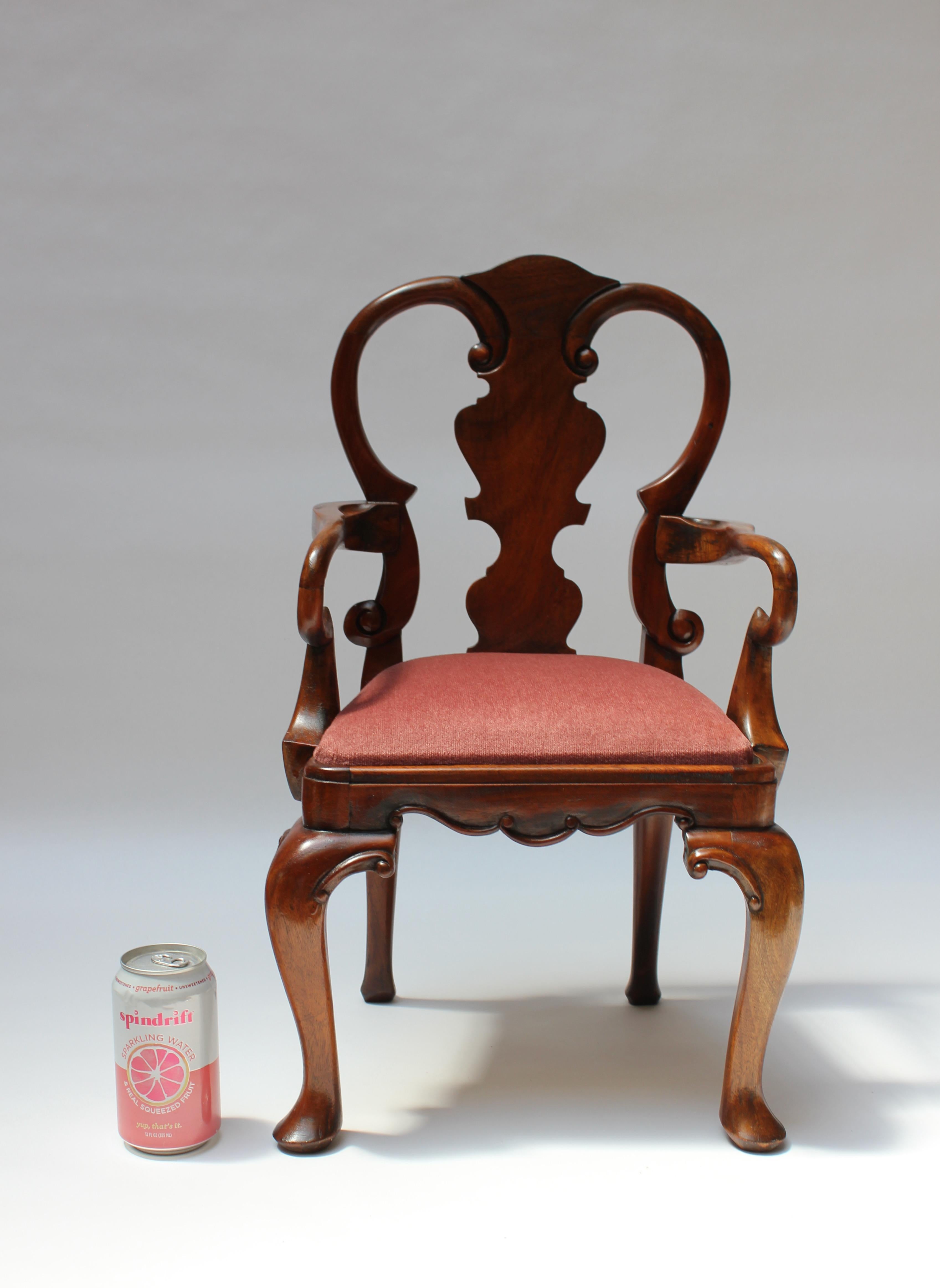 Miniature Queen Anne-style captain's / armchair, likely crafted as a Salesman Sample to advertise the full size model (ca. 1950s, England). 
Carved from solid cherrywood with dramatic cabriole legs and a deeply carved slat back. 
Small size: H: