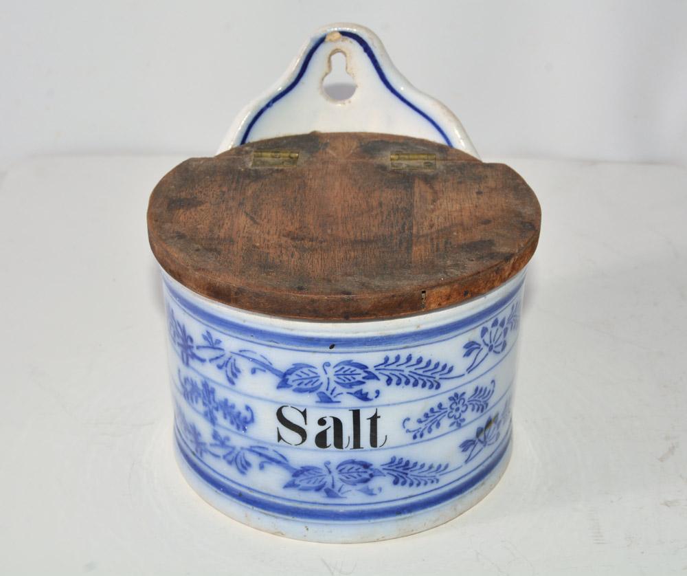 The vintage flow blue and white canister is labeled Salt. It has a wood hinged lid and a hole for hanging.