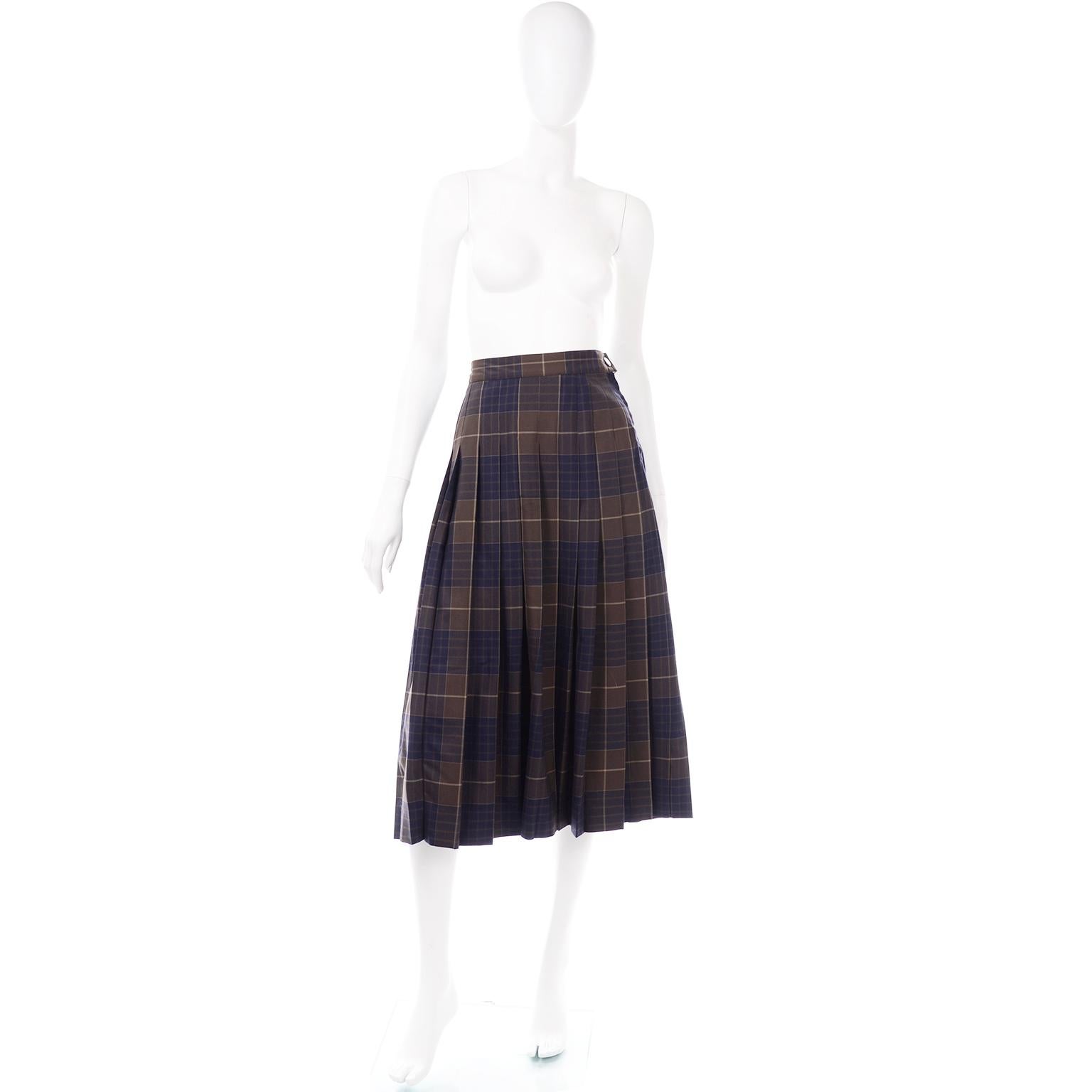 This is a lovely midi length pleated wool skirt by Salvatore Ferragamo in an olive brown and navy blue plaid. It is 100% wool, with knife pleats with a fixed waistband, and a zipper and button at the side for closure. We love the highlands look of