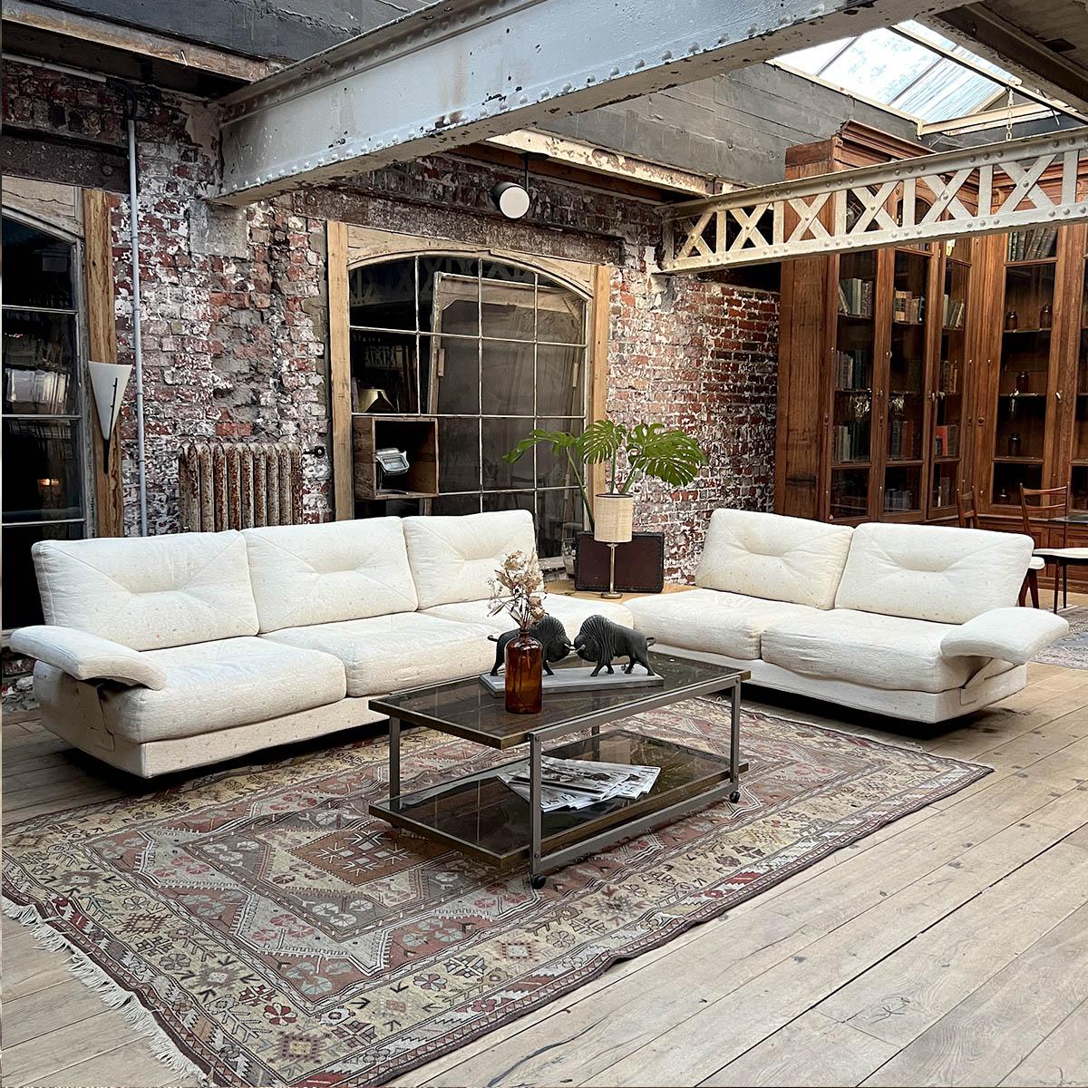 This elegant modular sofa by Saporiti exemplifies the bold and comfortable aesthetic of Italian design from the 1980s. Featuring a soft ivory upholstery with subtle pastel speckles, it combines plush comfort with sculptural lines. The wide armrests