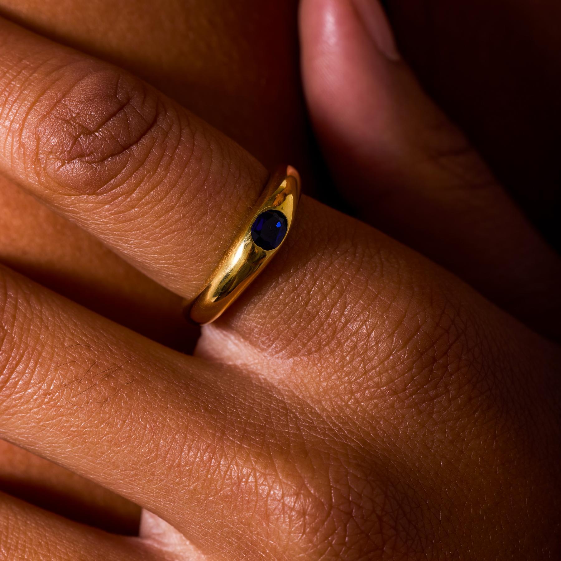 Dieses elegante und schlichte Vintage-Band aus den 1960er-Jahren zeigt einen ovalen Saphir in einer glatten Lünette aus leuchtendem 18-karätigem Gelbgold mit einem kräftigen Farbton. Der tiefblaue Edelstein strahlt zeitlose Schönheit aus, seine